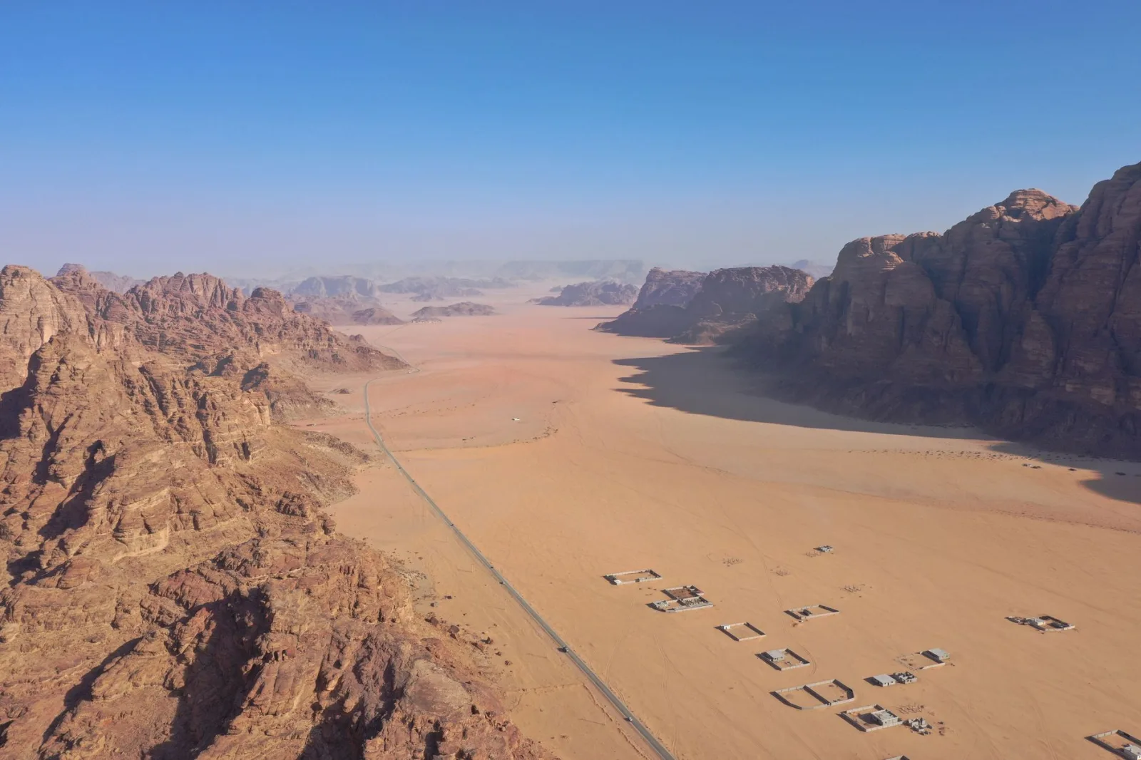 Stunning aerial view of Wadi Rum's expansive desert landscape in Jordan, featuring rock formations and clear blue skies.