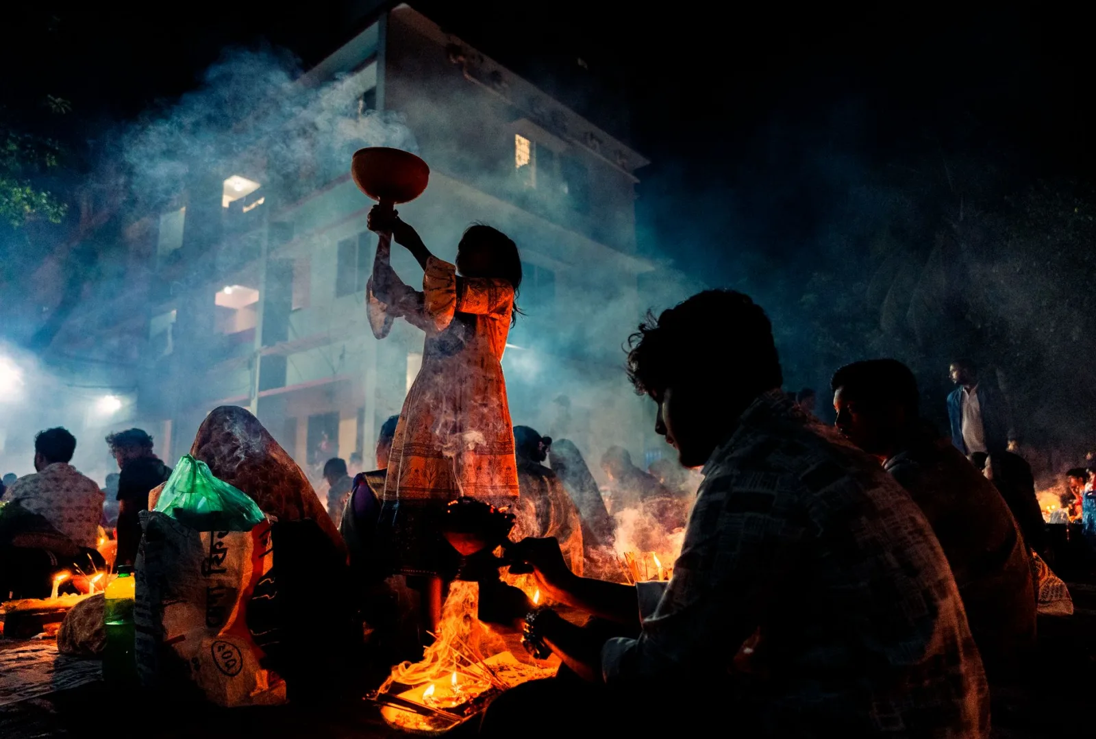 A vibrant night ceremony in Bangladesh with people engaged in traditional activities.