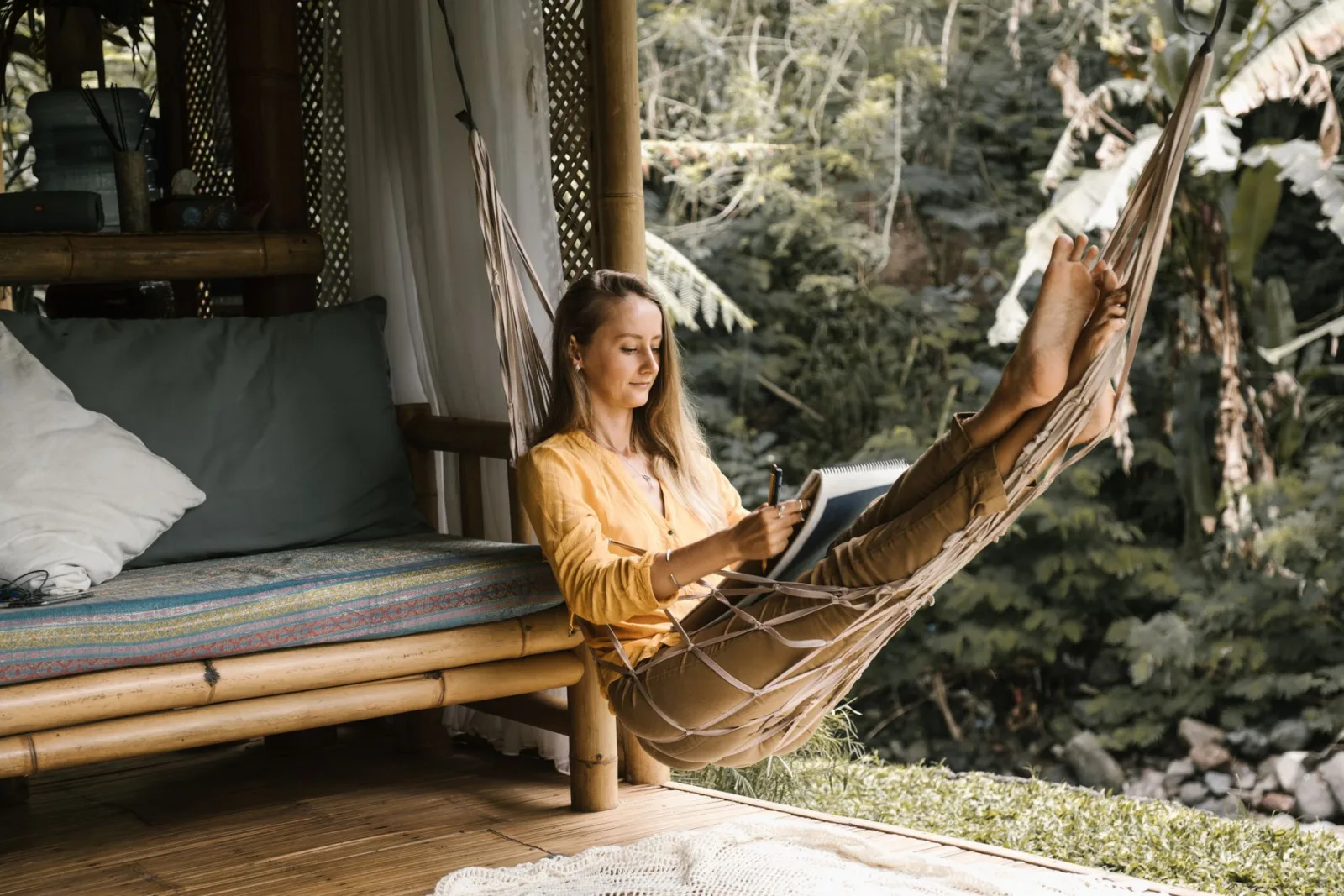 Serene scene of a woman sketching in a hammock surrounded by lush greenery.