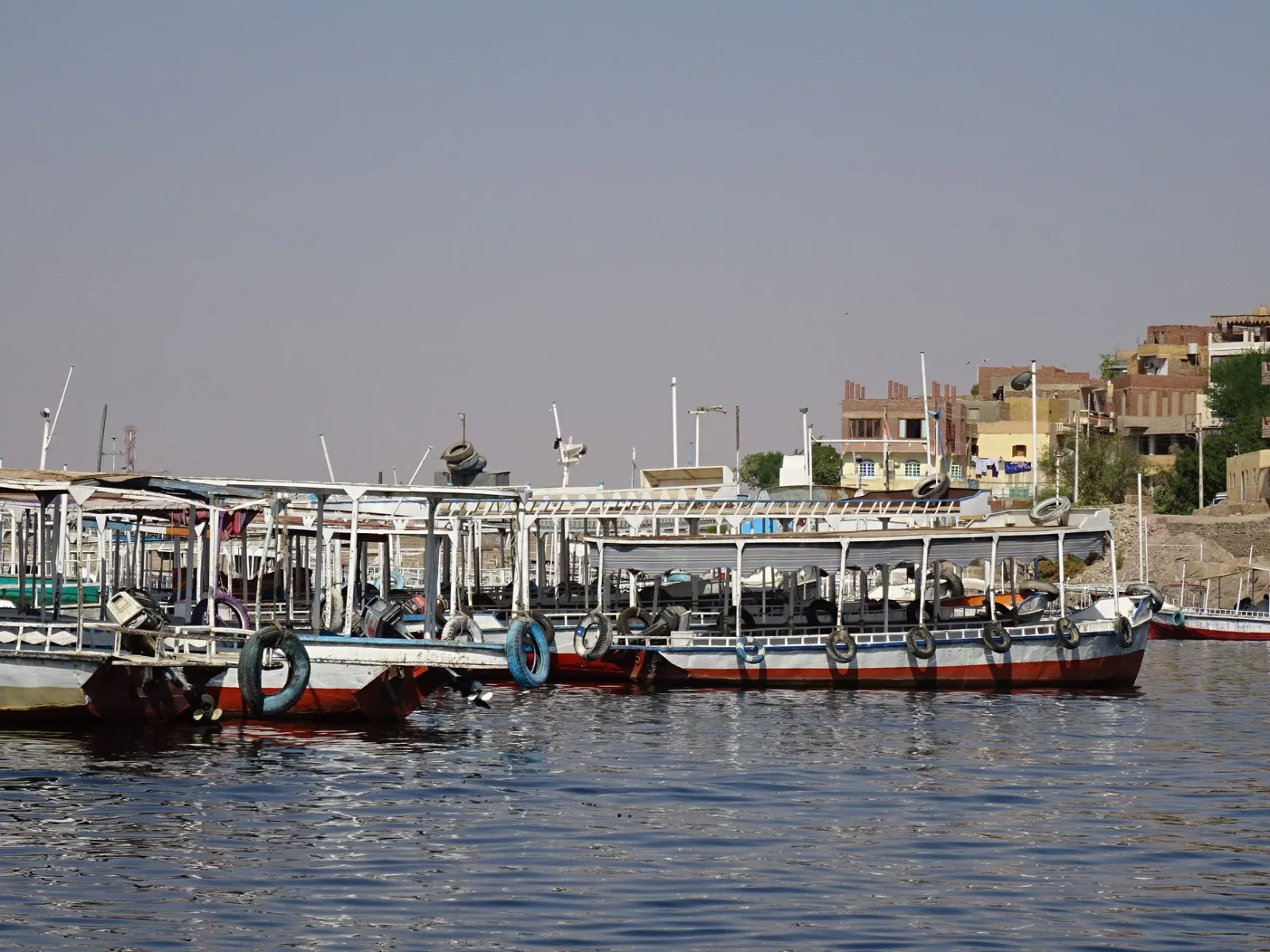 Colorful boats docked along the Nile River in Egypt under a clear blue sky.