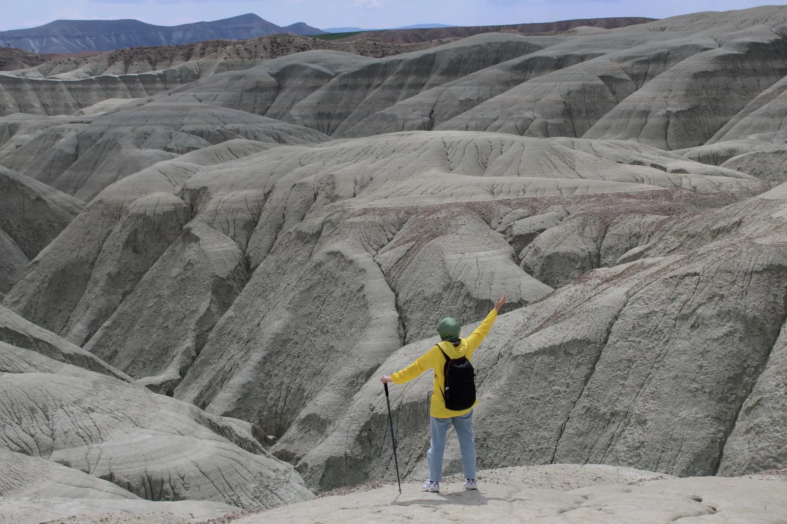 Person trekking in rugged landscape with unique geological formations.