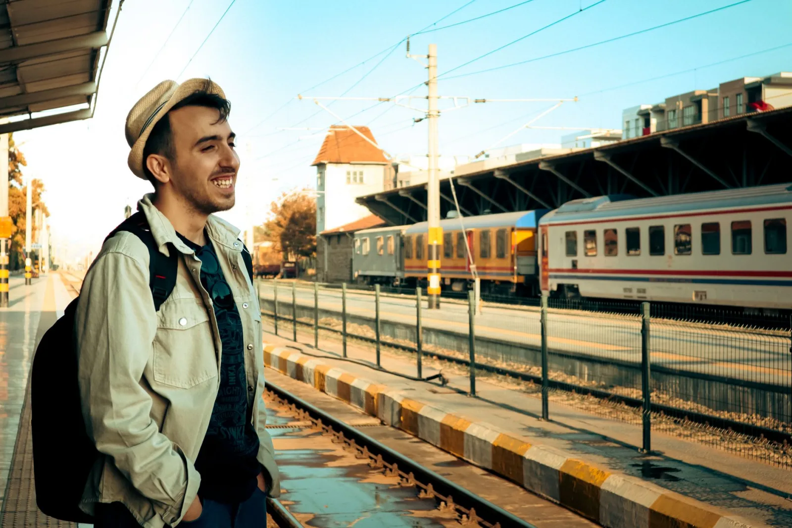 A cheerful traveler at Balıkesir train station, Türkiye, enjoying a sunny day.