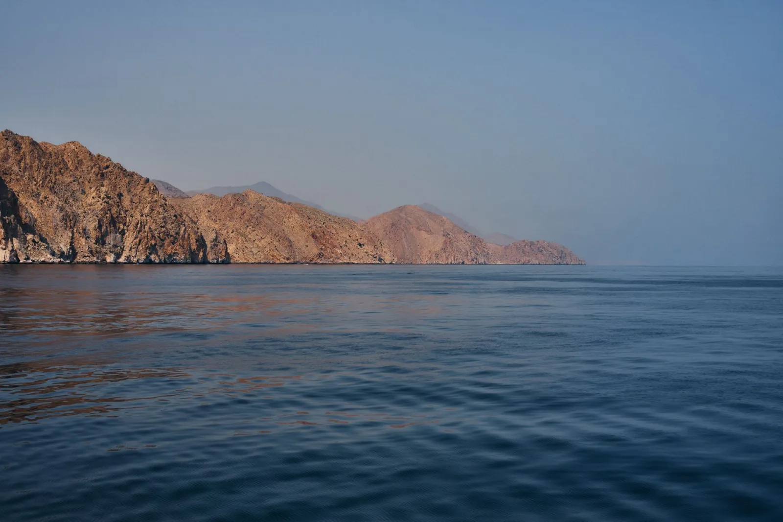 Peaceful seascape of Musandam's rugged coastline under a clear sky.