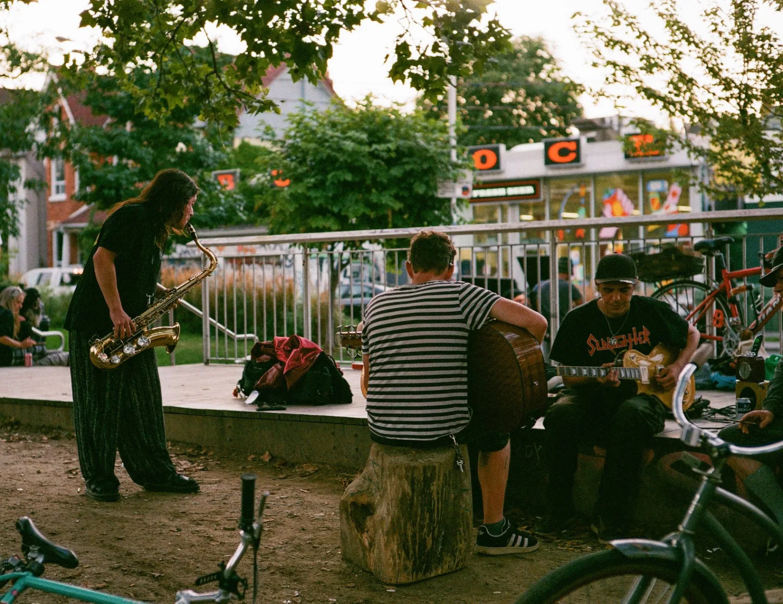 Street musicians playing saxophone and guitar in a Toronto park, capturing urban life and culture.