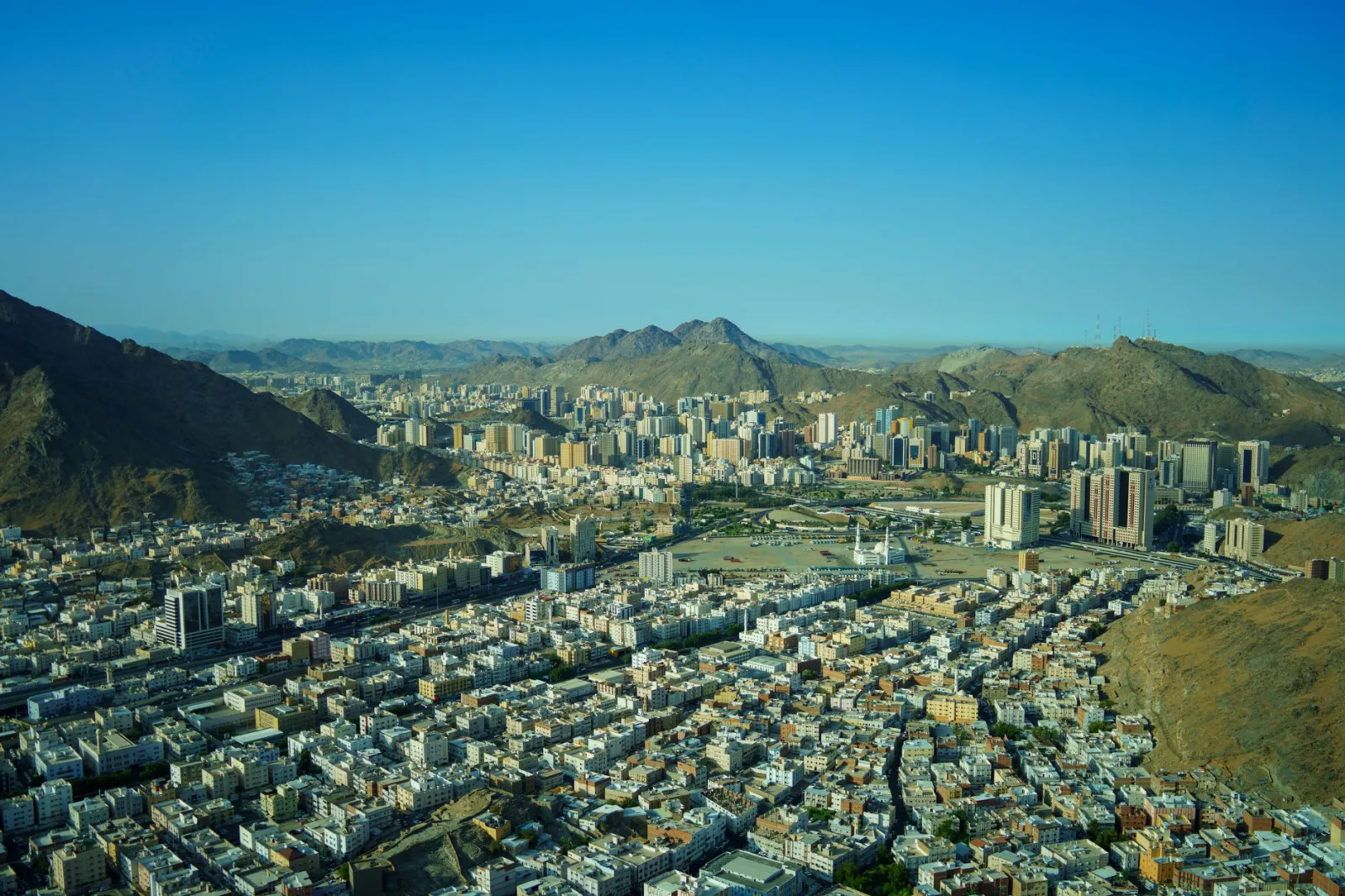 Stunning cityscape of Makkah with mountains and modern architecture under a clear blue sky.