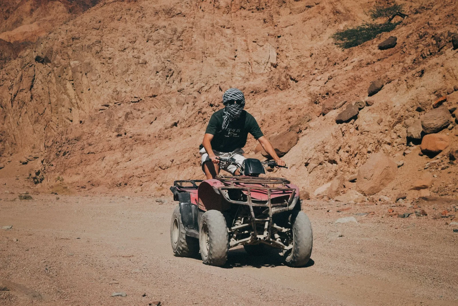 Man riding a quad bike through the rugged desert terrain of Dahab, Egypt.