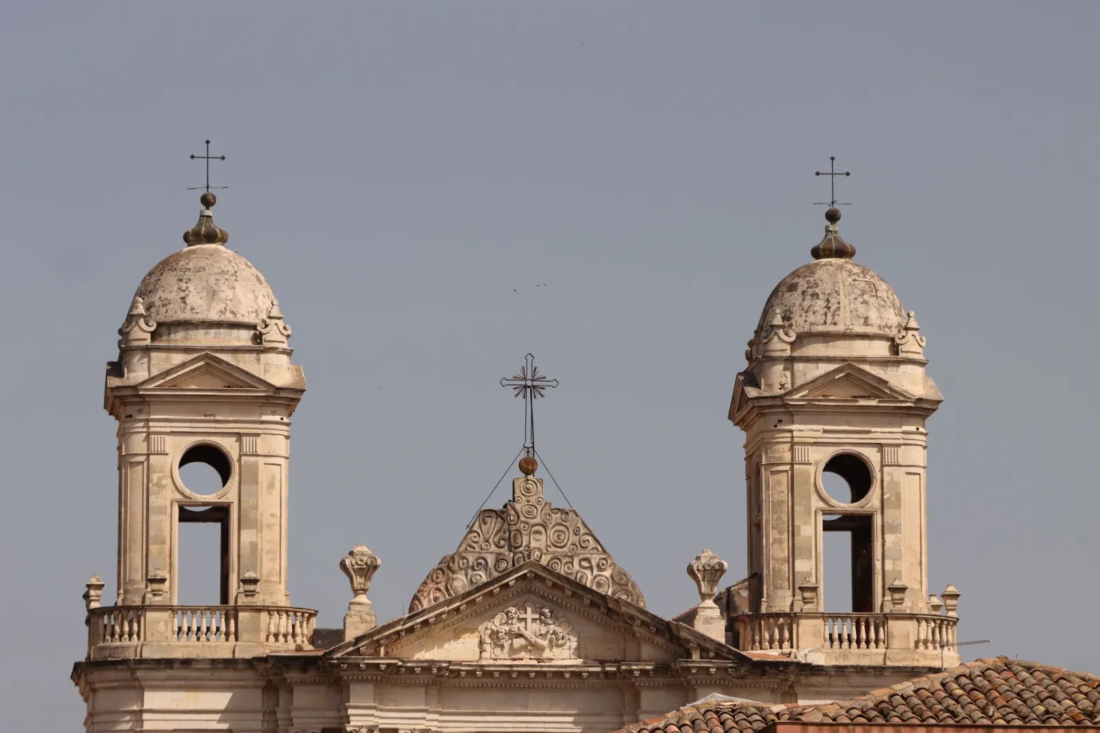 Majestic baroque-style cathedral towers under a clear sky in Catania, Sicily, Italy.
