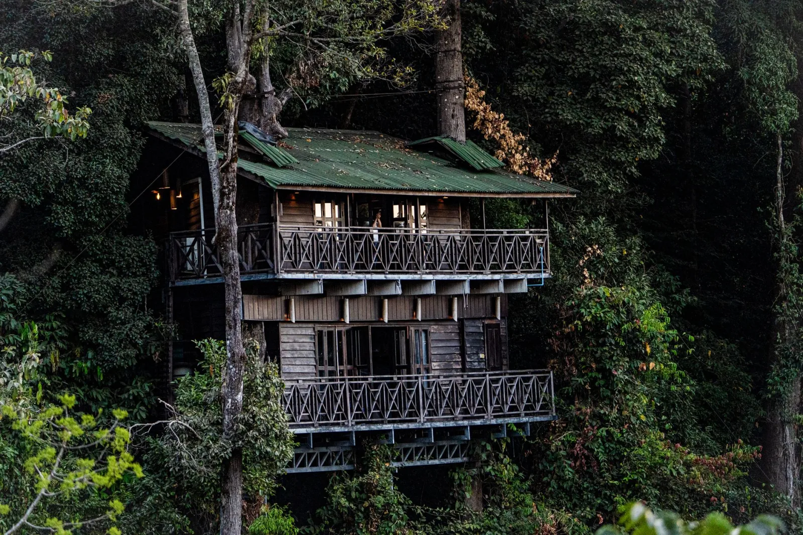 A cozy wooden treehouse cabin nestled among lush forest greenery during daylight.