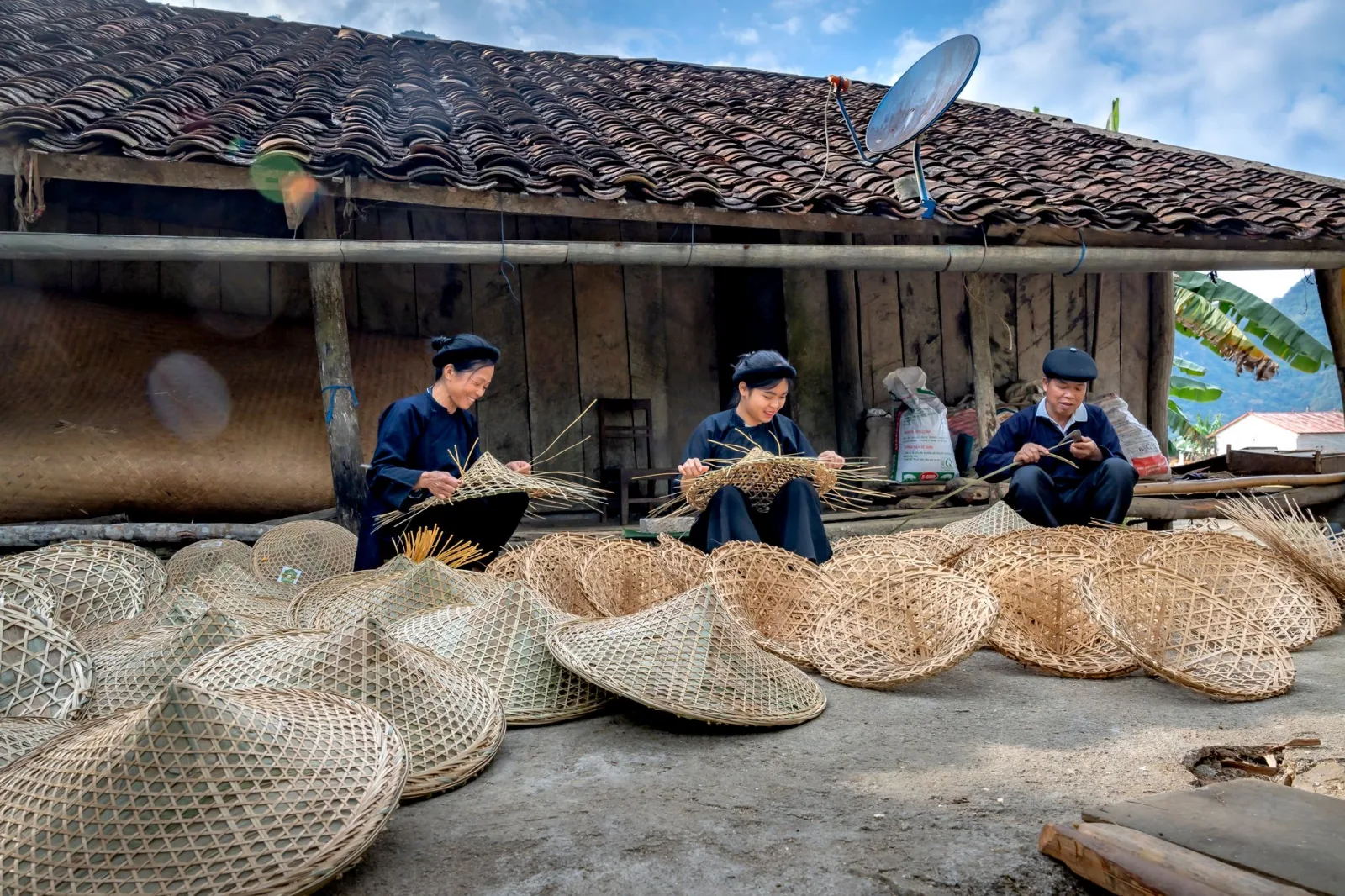 Artisans weave bamboo baskets in a rural village, showcasing traditional craftsmanship.