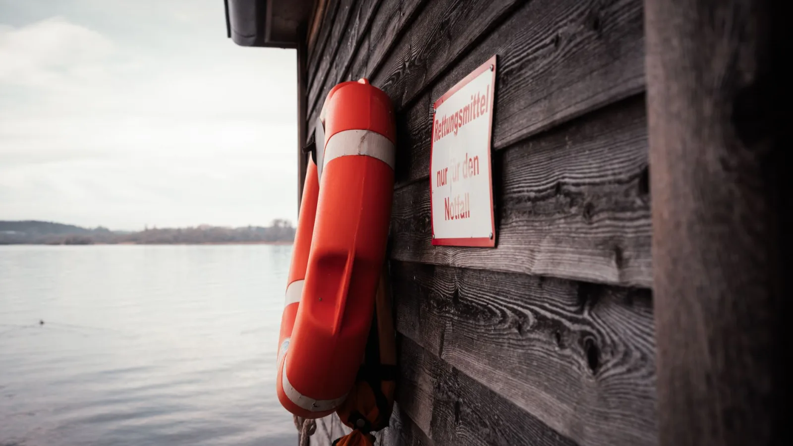 Orange lifebuoy on a wooden boathouse by a lake in Bavaria, Germany.