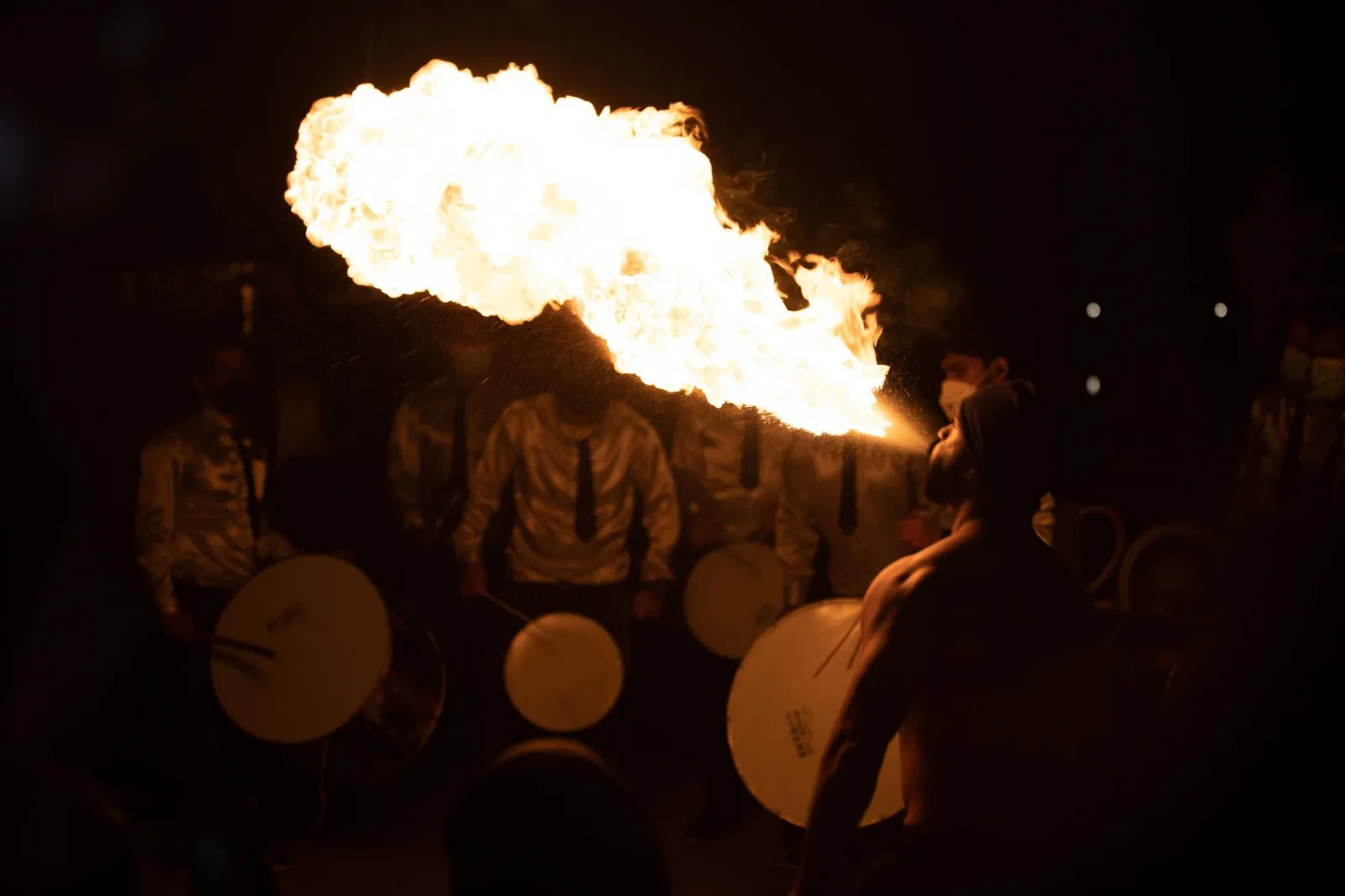 A captivating fire breather performing during a night festival with drummers in Bahrain.