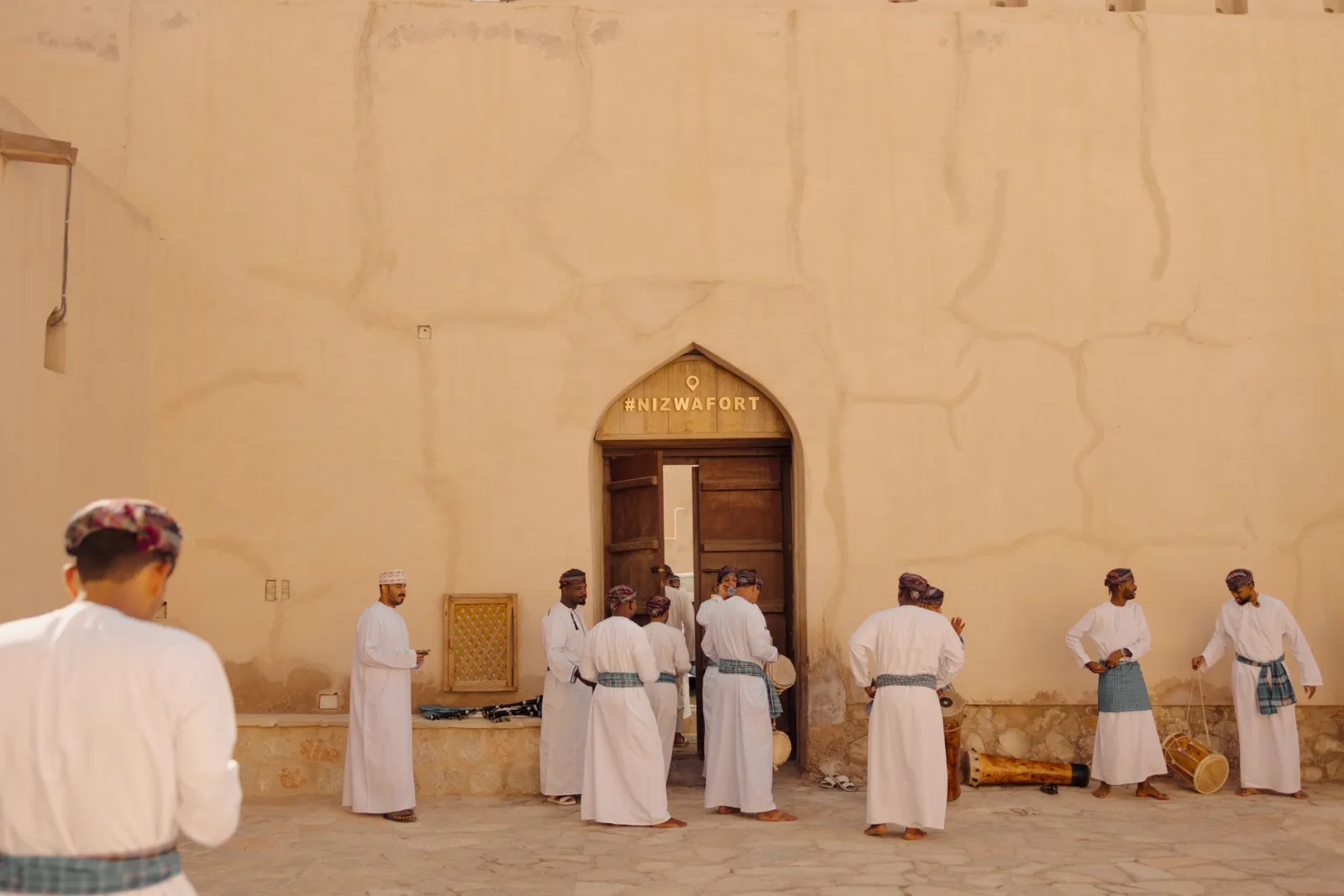 Group of men perform a traditional Omani dance in front of Nizwa Fort, Oman.