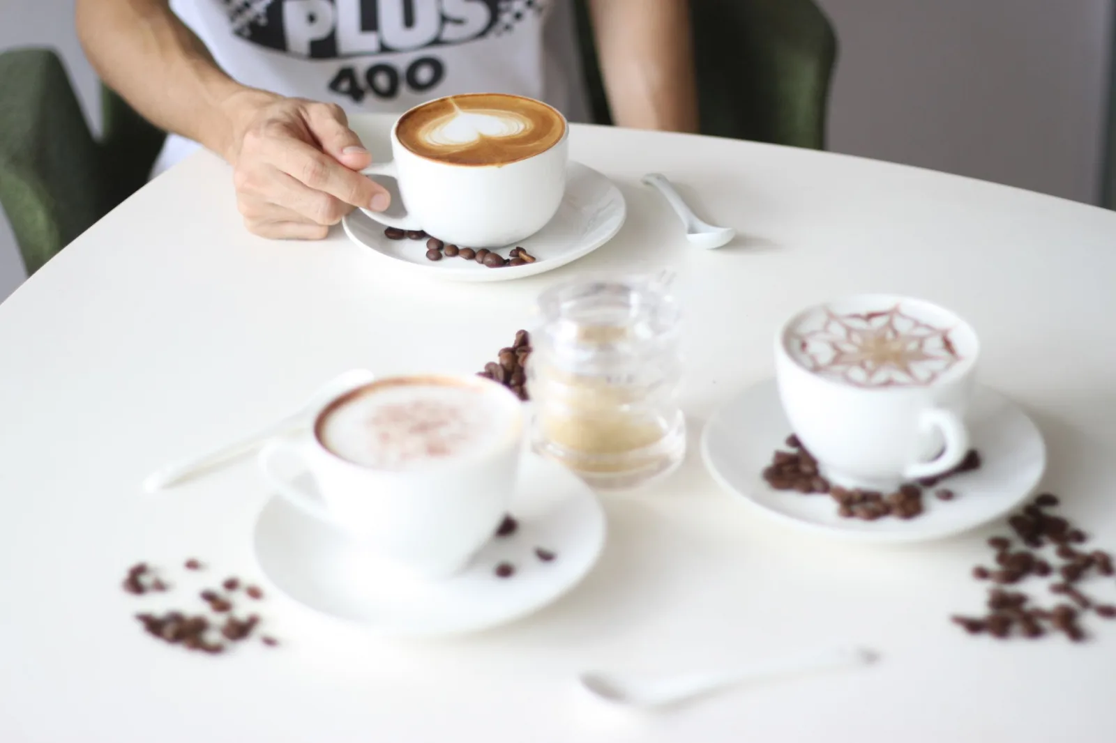 A stylish arrangement of various coffee cups on a café table with a person reaching for one.