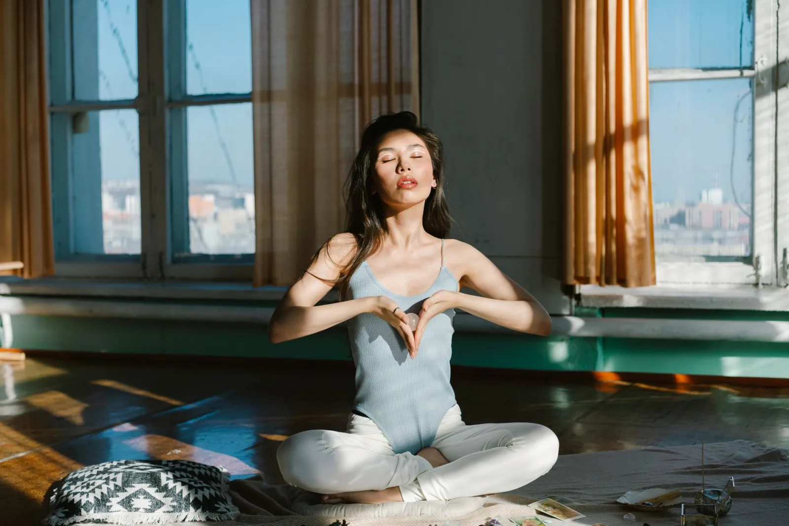 Full body of peaceful ethnic female with natural chakra gemstone crystal sitting with crossed legs during spiritual session
