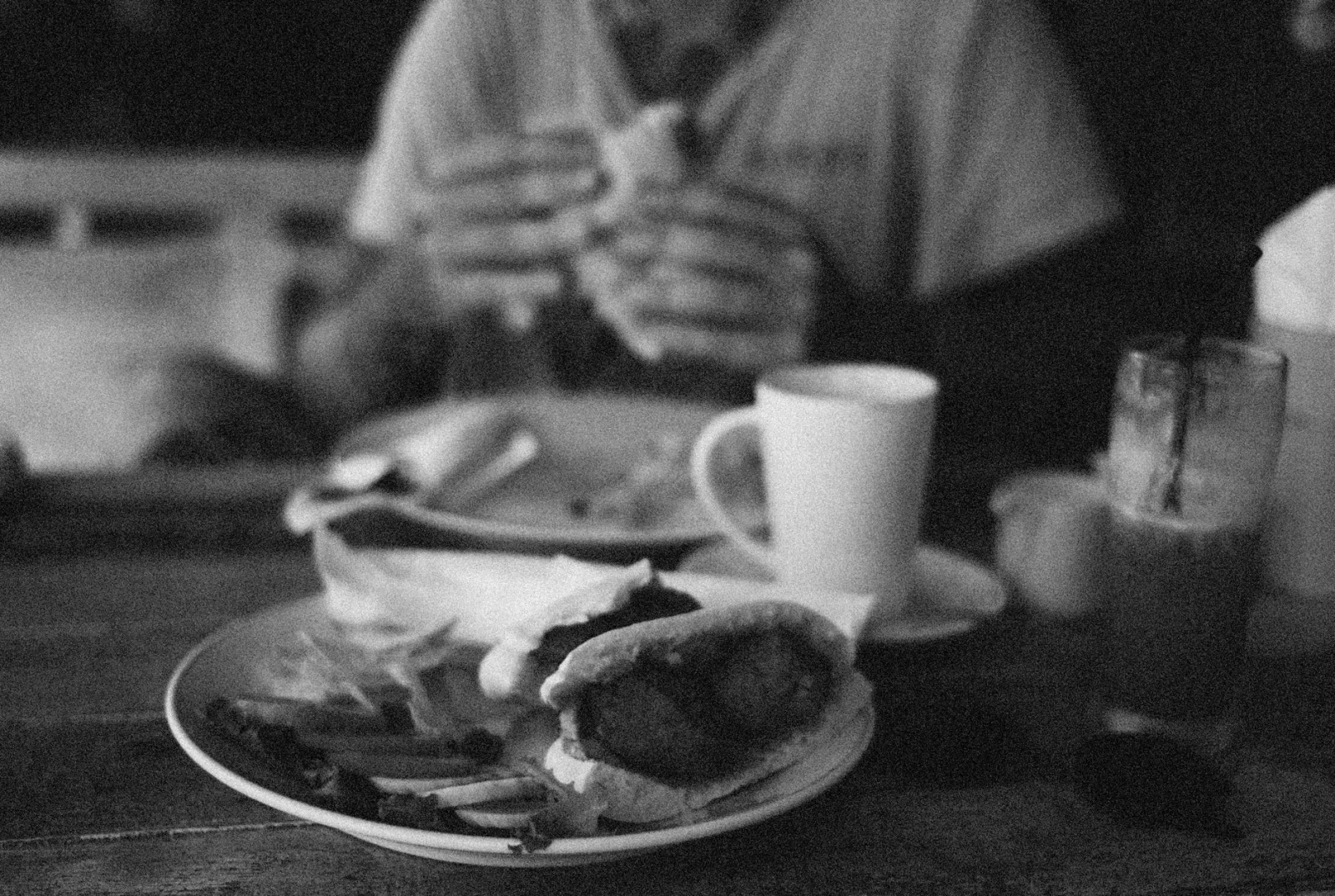 Black and white close-up of a meal with cup on a wooden table.