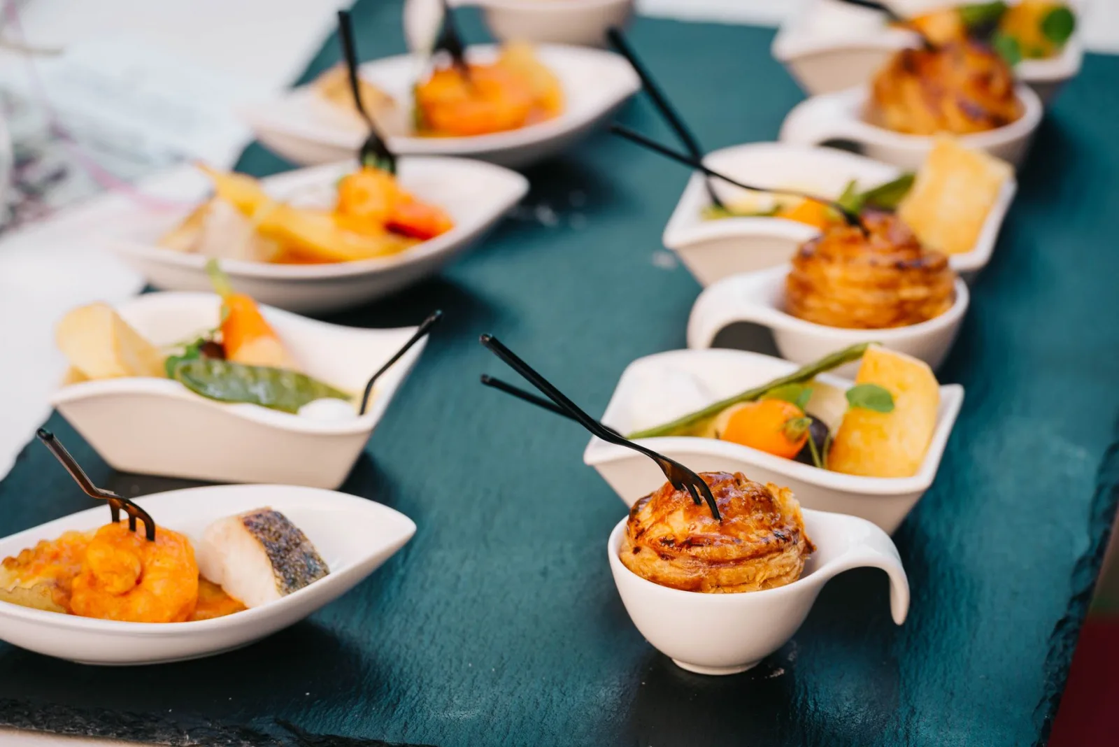 A selection of gourmet canapés beautifully arranged on a black slate tray for a sophisticated presentation.