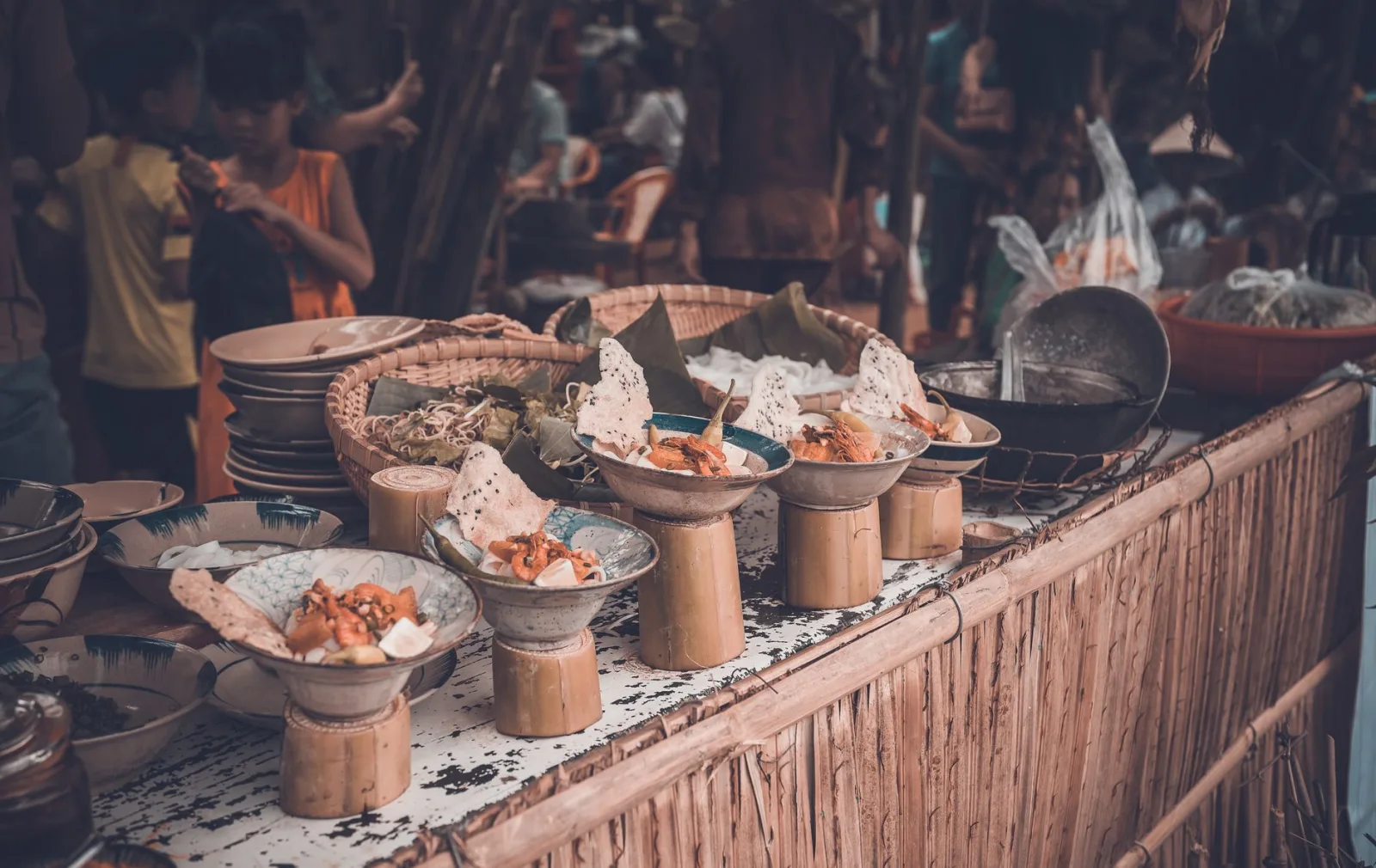 Vibrant street food market with various dishes displayed in unique bowls and plates.