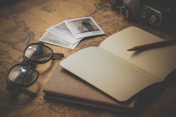 Stylized flat lay of a vintage travel journal with eyeglasses, photos, and a map background.