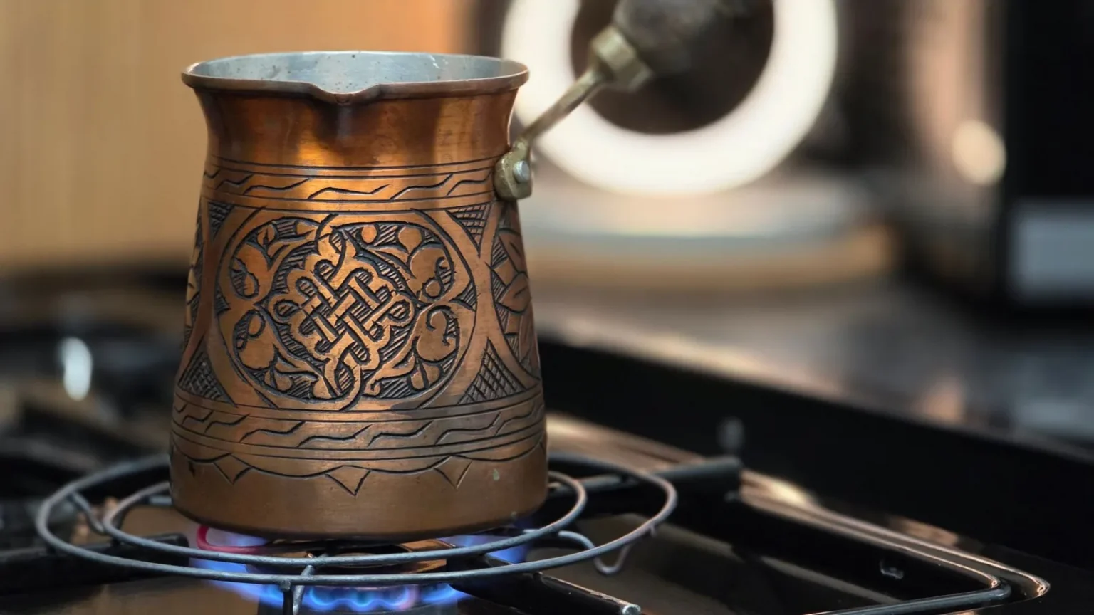 Traditional copper Turkish coffee pot brewing on a stove.