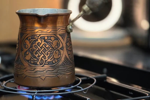 Traditional copper Turkish coffee pot brewing on a stove.