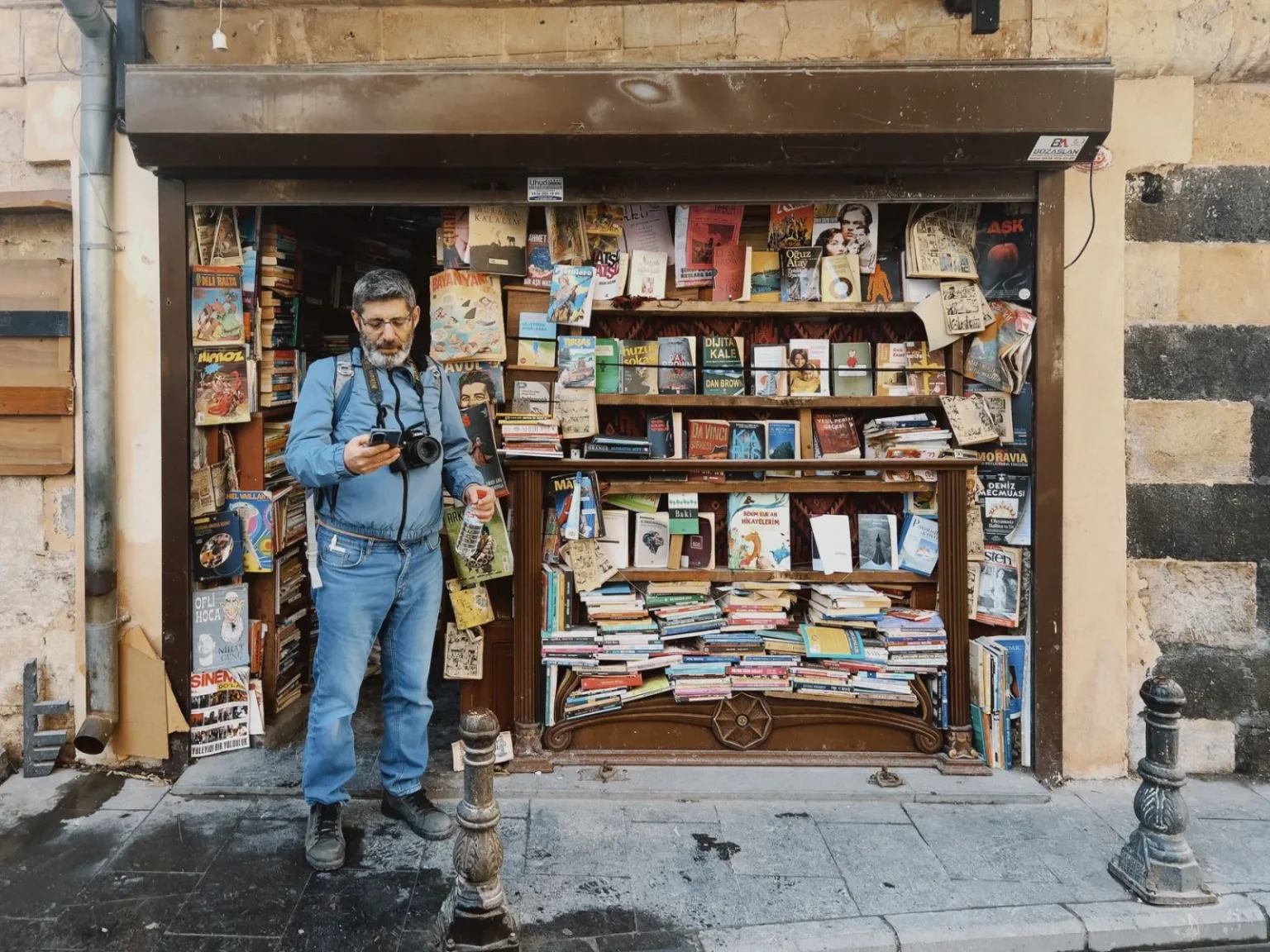 A quaint street bookstore stocked with diverse titles and a photographer capturing the moment.