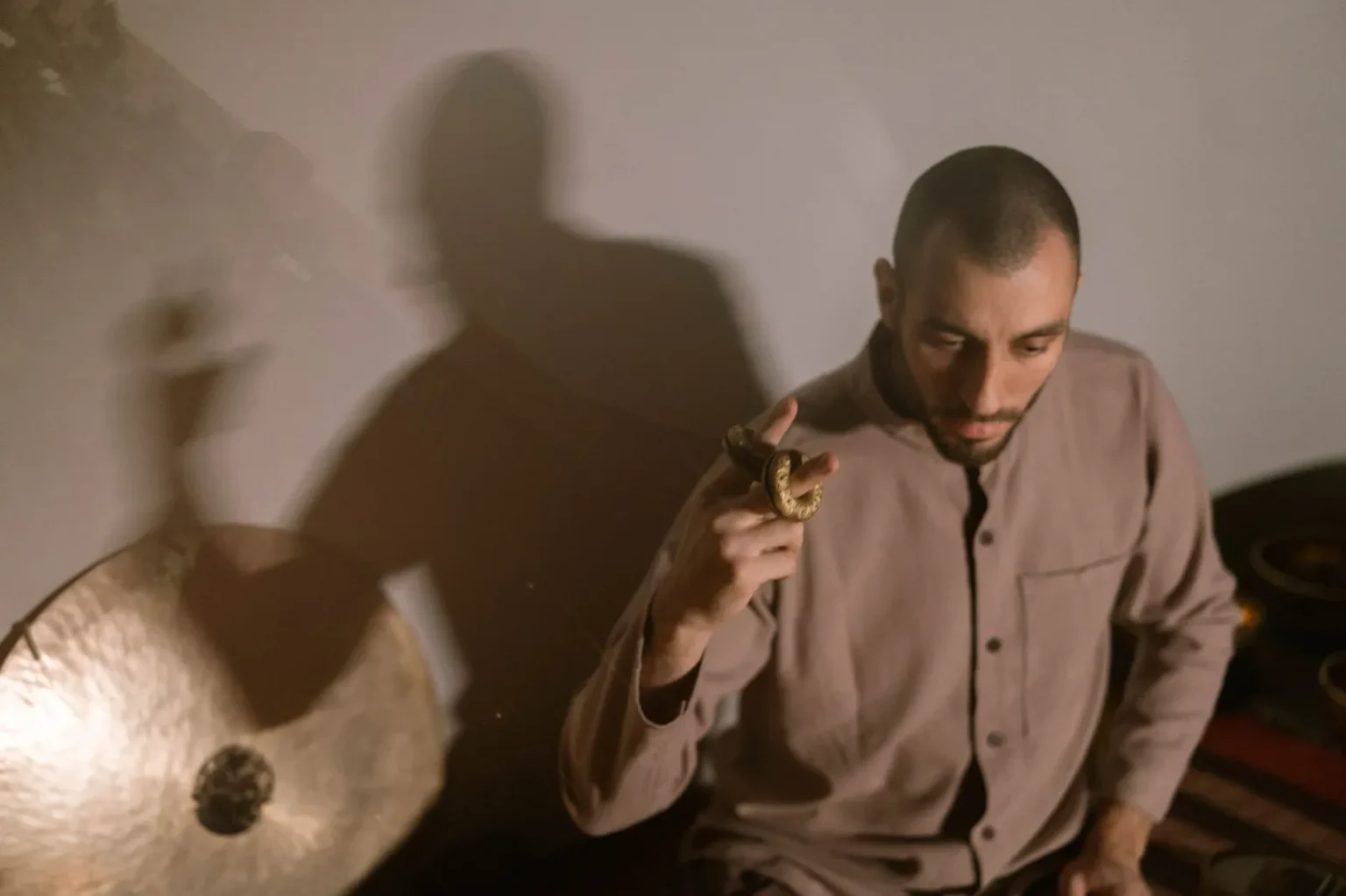 Meditative scene of a man using a gong and hudak to create relaxing sounds.