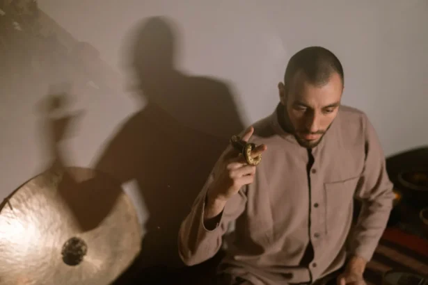 Meditative scene of a man using a gong and hudak to create relaxing sounds.