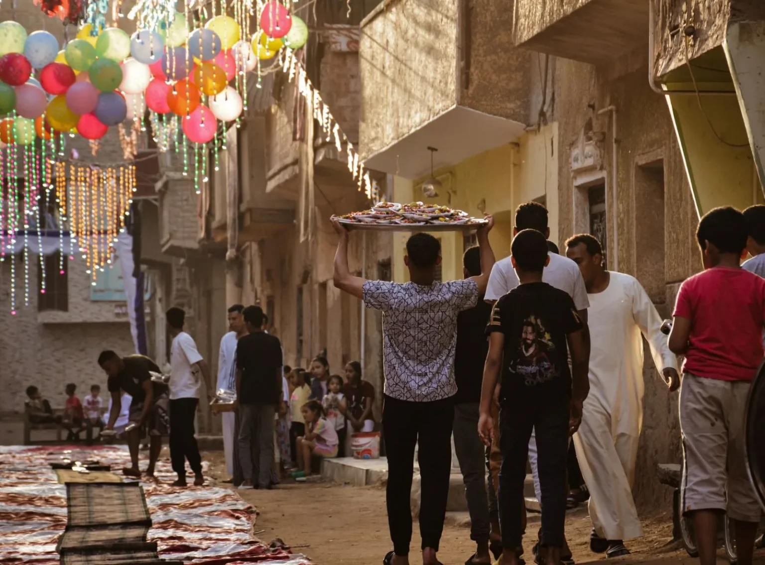 Vibrant street festival with balloons and people celebrating in traditional attire.