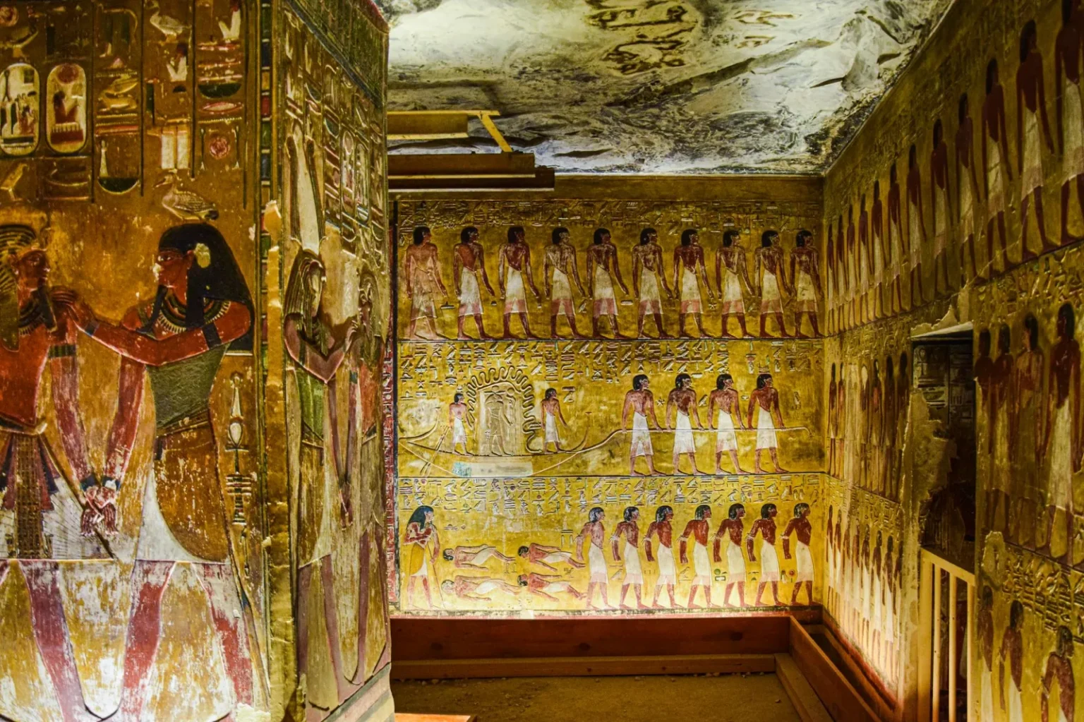 Colorful ancient Egyptian frescoes depicting historic scenes inside a tomb.