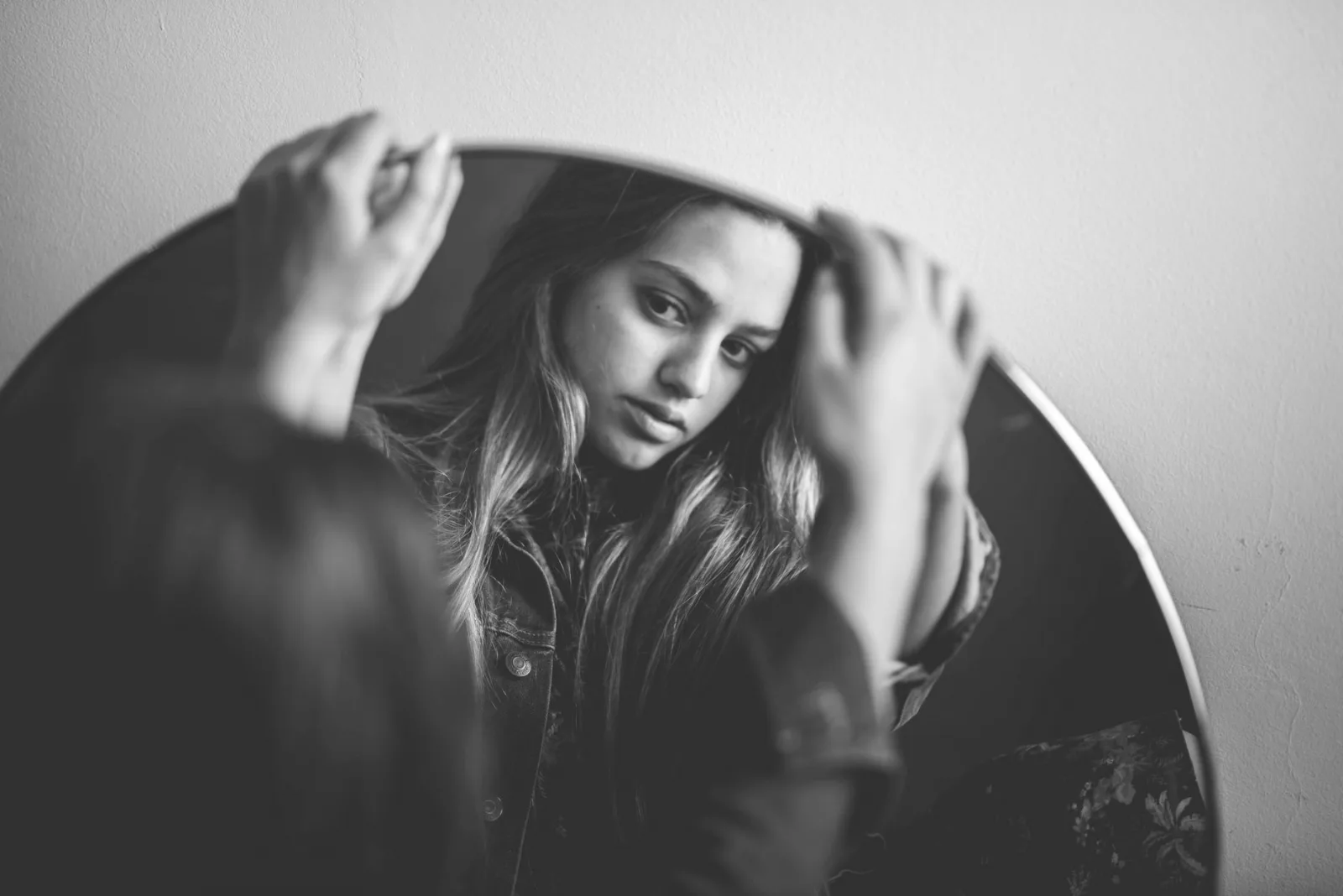 Elegant black and white portrait of a woman reflecting in a mirror.