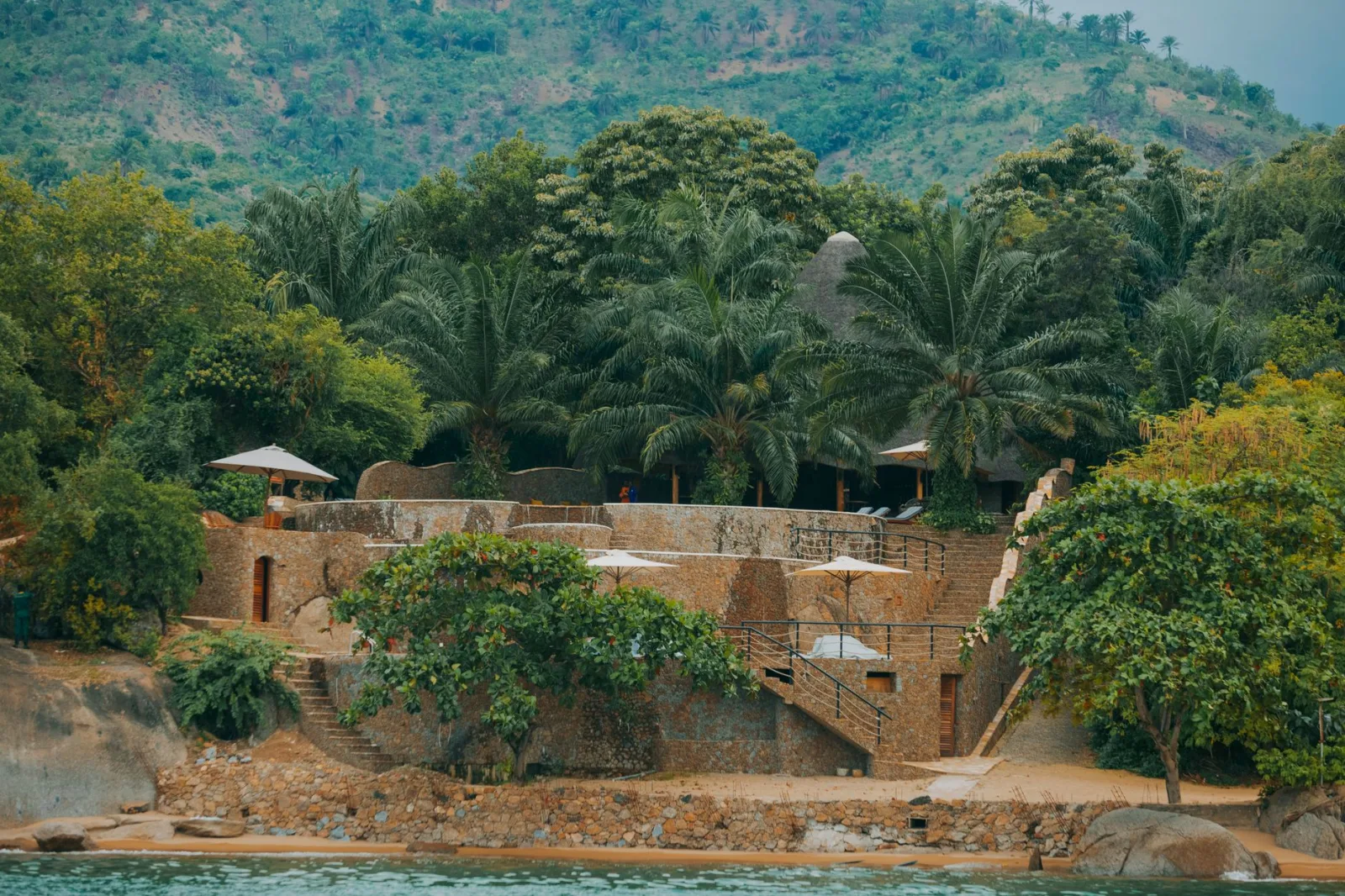 Charming stone retreat surrounded by lush tropical greenery near pristine water.