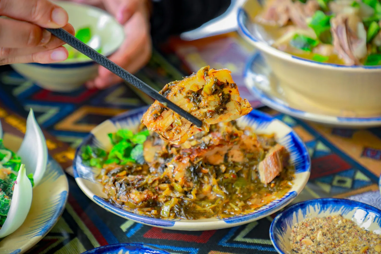 Close-up of a traditional Vietnamese pork dish with vegetables, captured indoors with chopsticks.