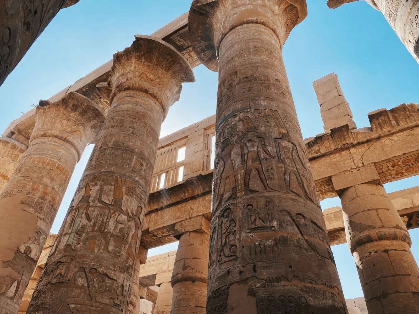 Impressive ancient Egyptian temple columns with hieroglyphics under a clear blue sky.