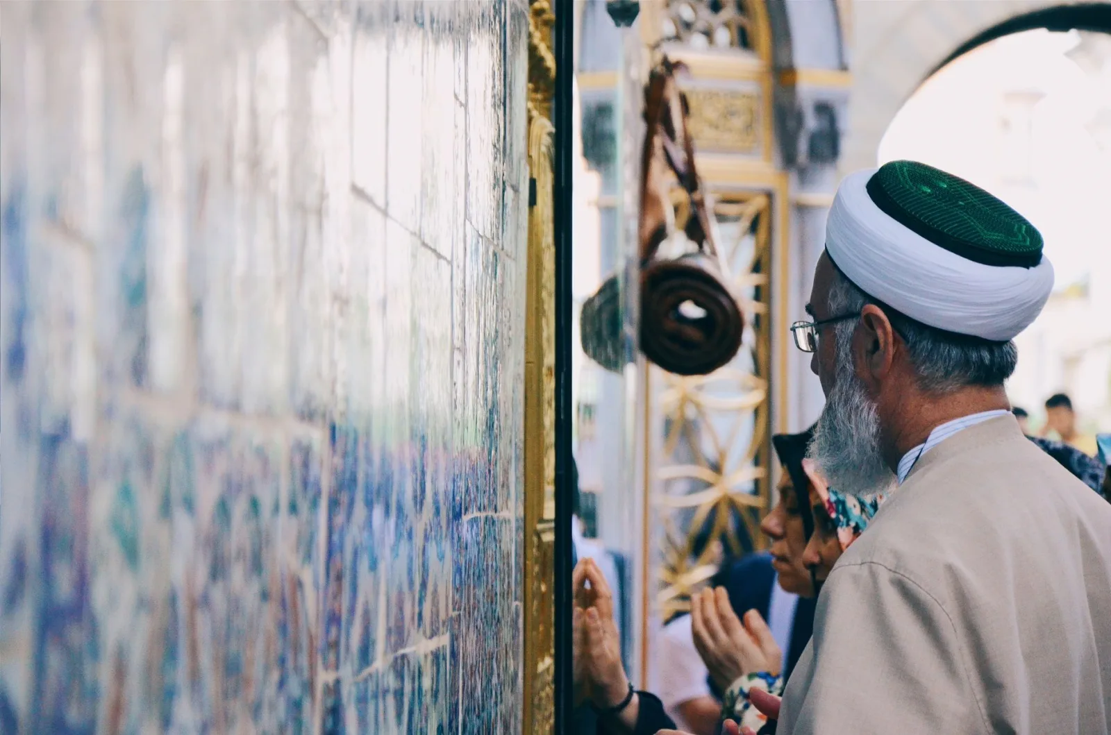 A religious gathering with people praying at a beautifully decorated temple wall.