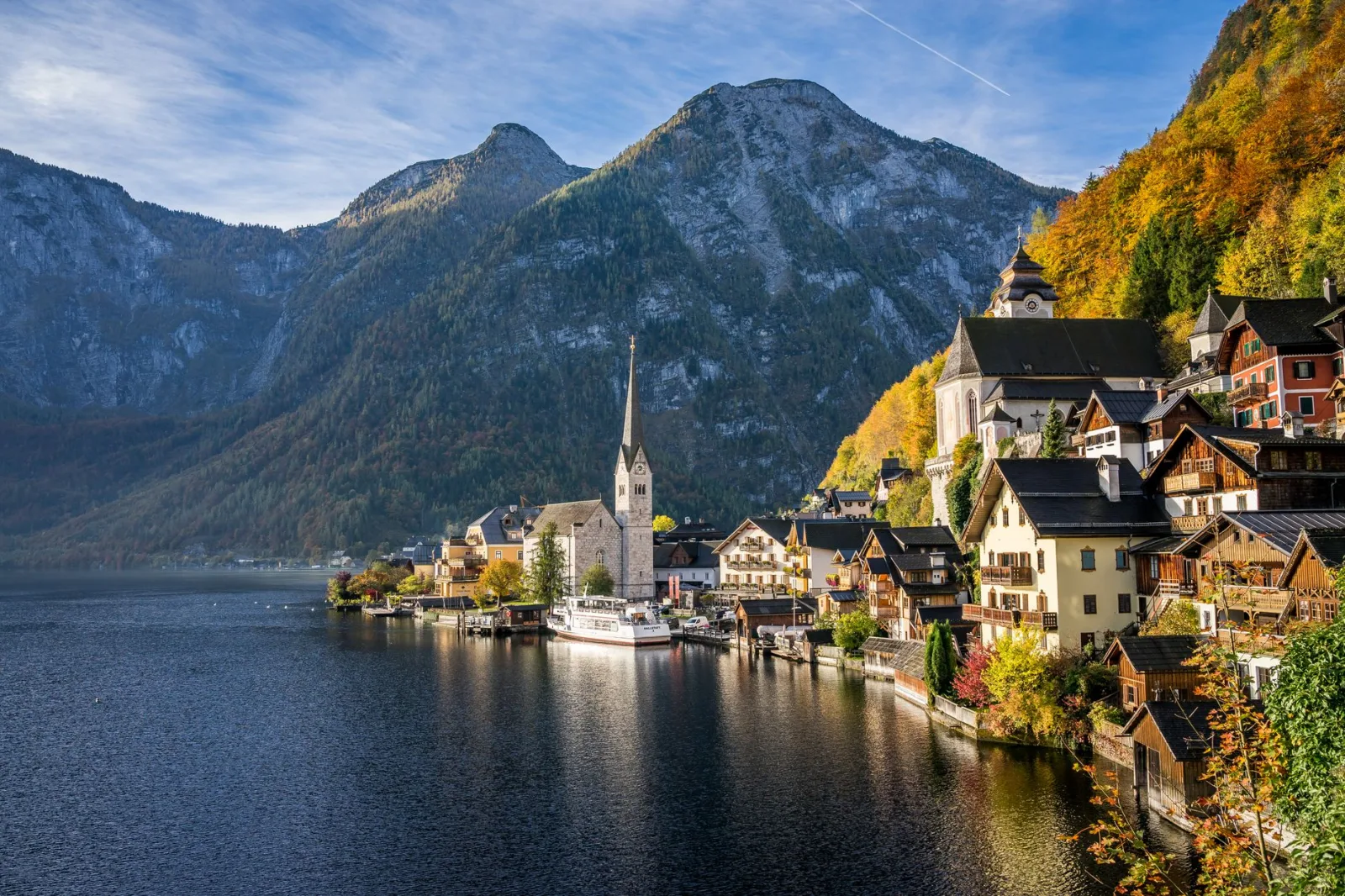 Charming lakeside village of Hallstatt with autumn colors, mountain backdrop, and picturesque architecture.