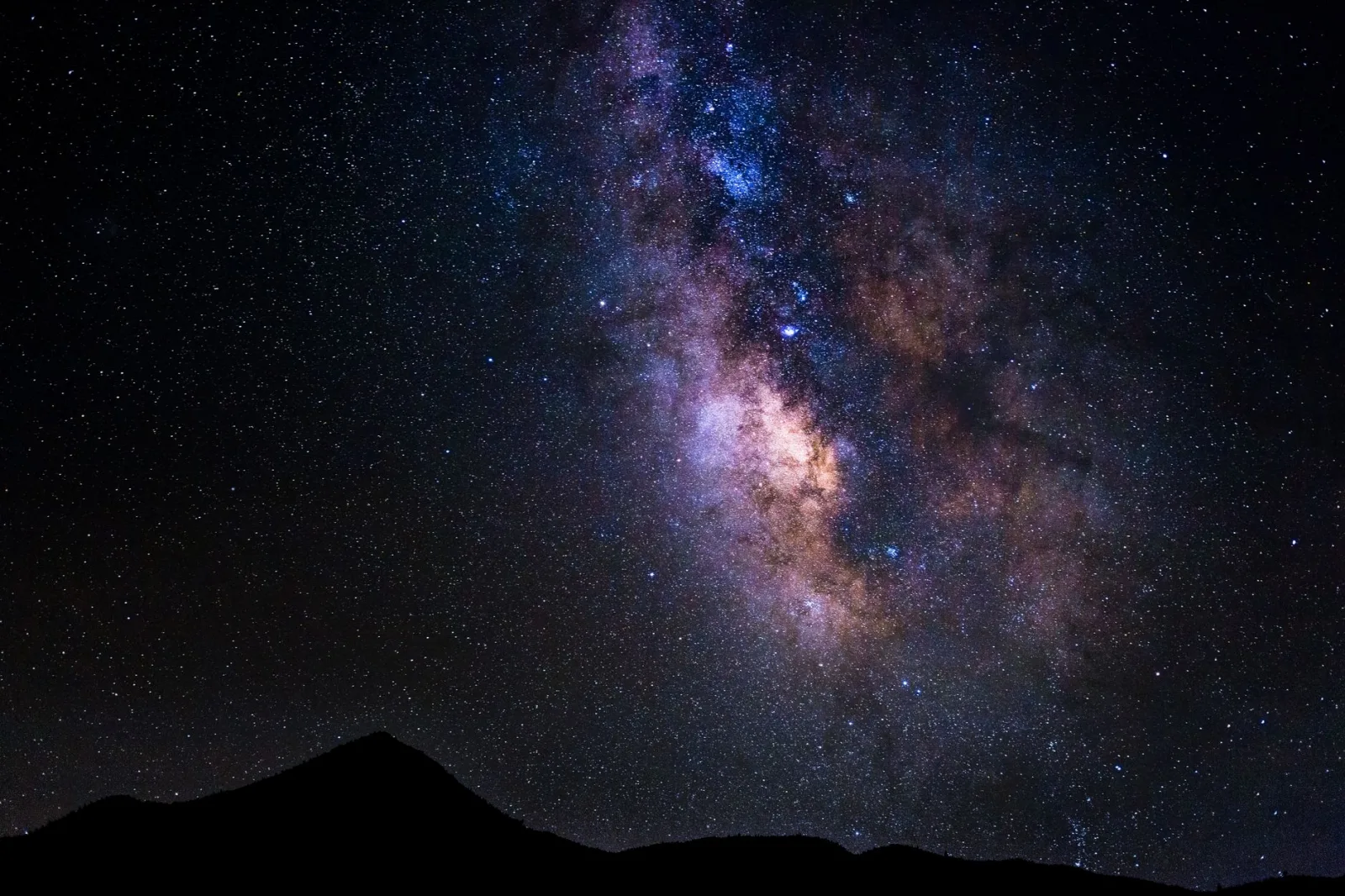 Captivating night sky featuring the Milky Way above silhouetted mountains in Onyx, California.