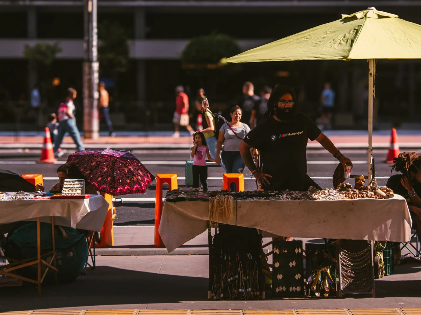 A lively street vendor scene in an urban setting featuring diverse people and colorful market stalls.