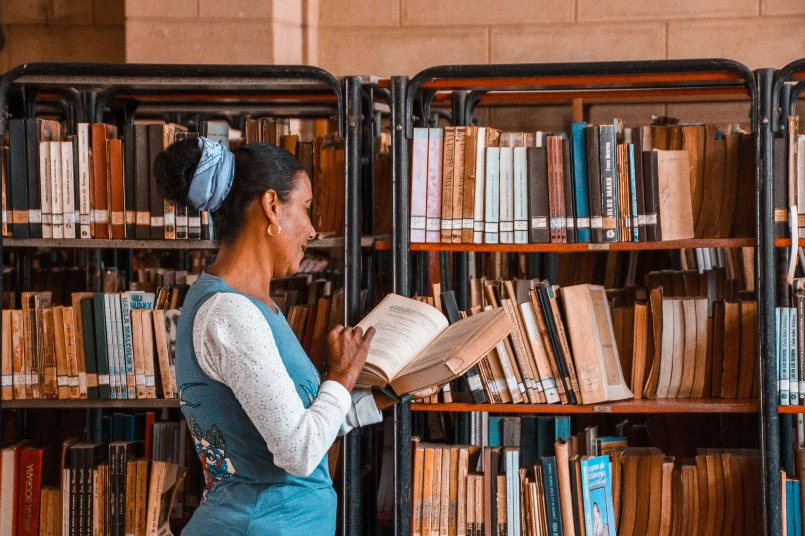 Woman admires books in a warm and organized library environment.