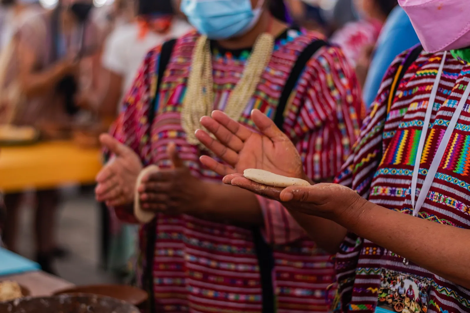 Artisan making tortillas by hand during a vibrant cultural festival market.