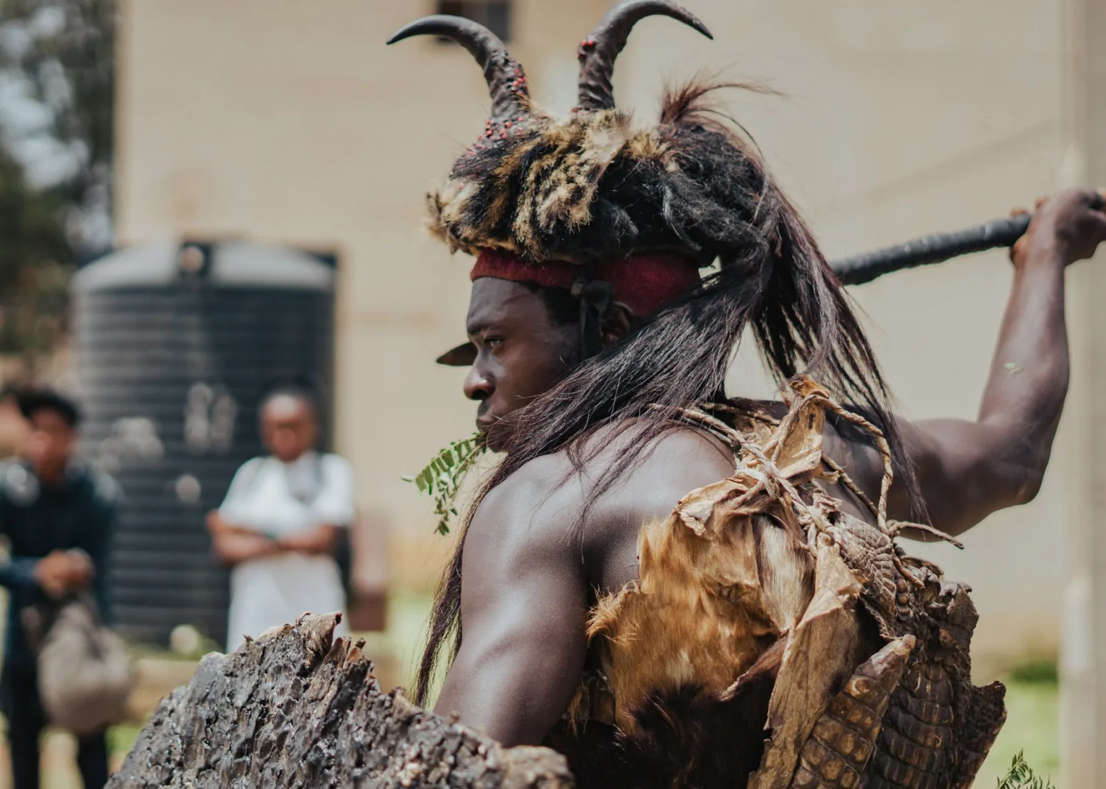 A traditional Nigerian cultural performer wearing an ornate costume with a backdrop of spectators.