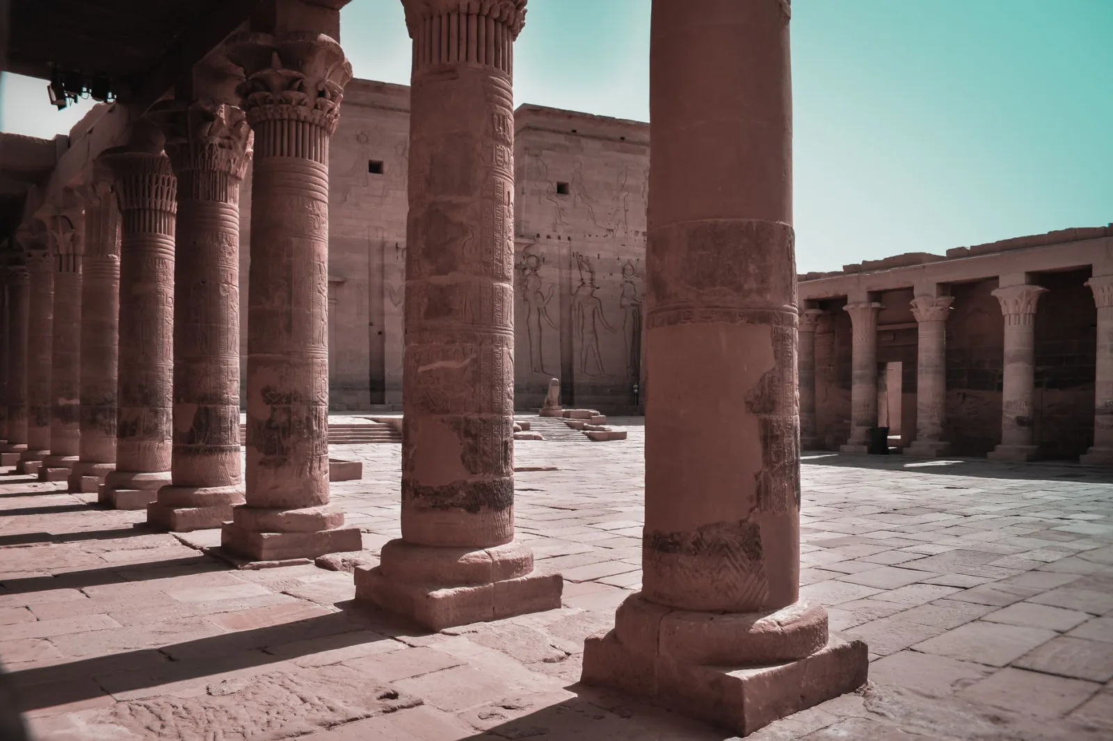 Majestic columns in an ancient Egyptian temple courtyard, Aswan, showcasing intricate carvings.