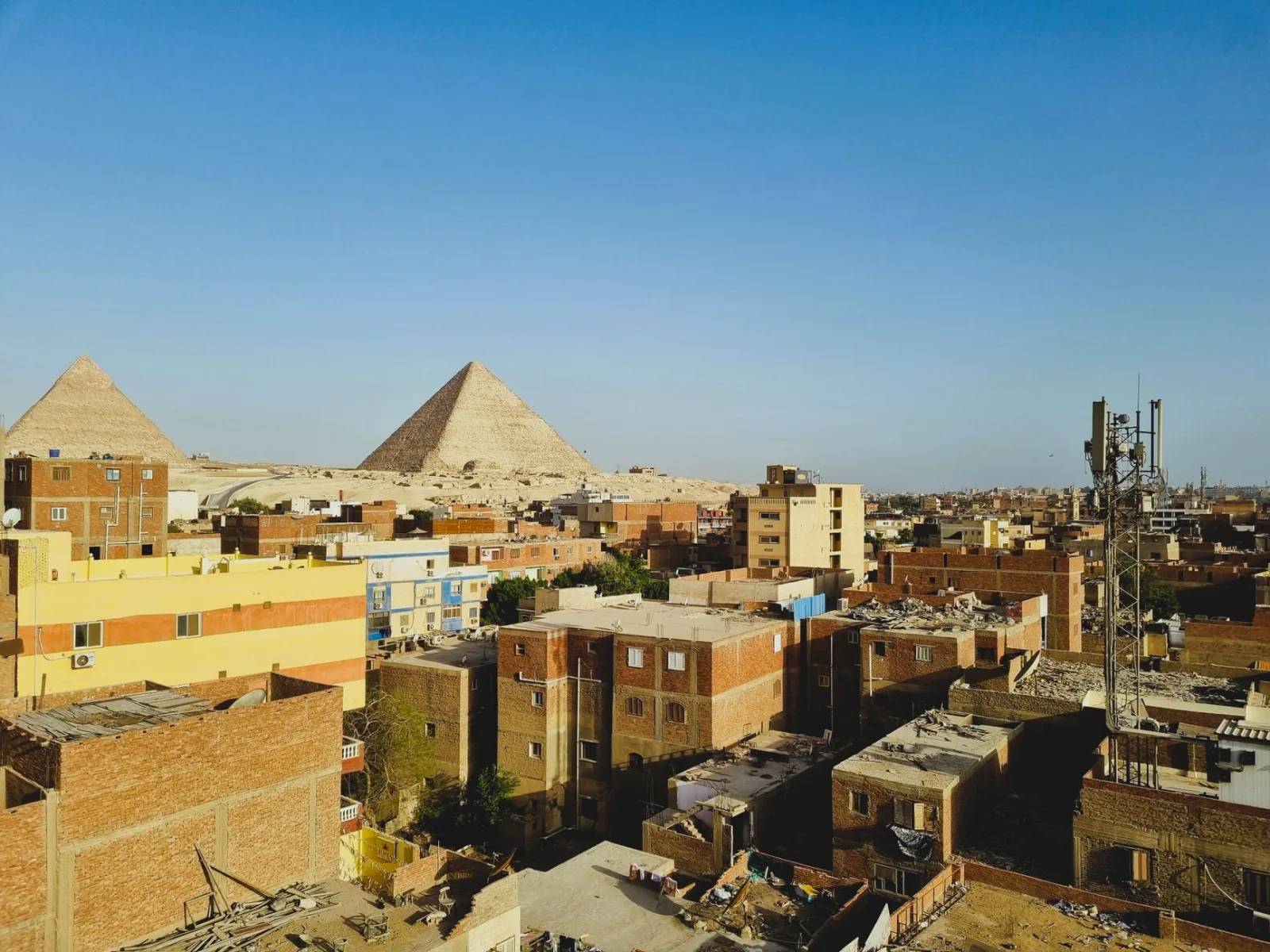 Urban landscape with Giza Pyramids under clear sky, Egypt.