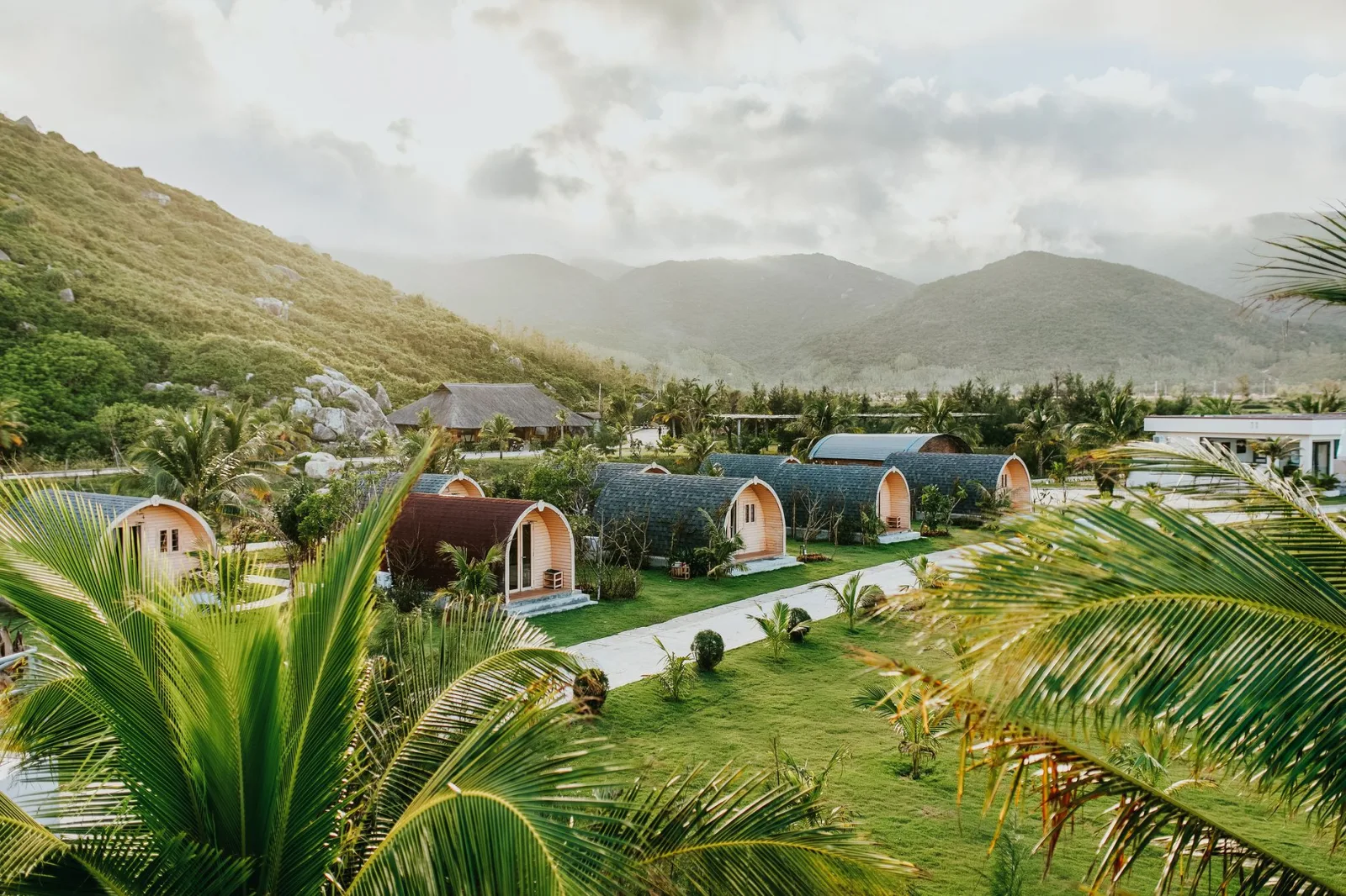 Beautiful tropical resort with villas nestled amidst palm trees and hills, perfect for a summer getaway.