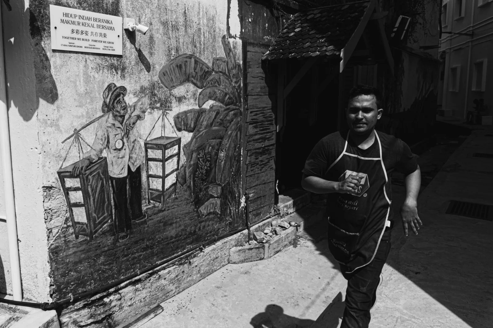 Man walks by street mural in urban black and white photography.