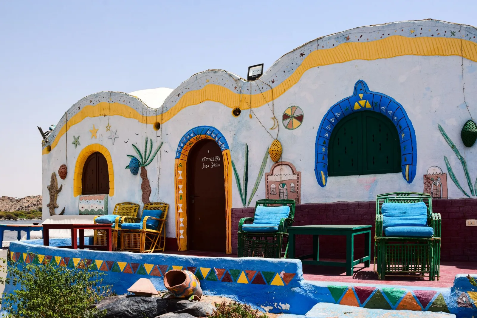 Vibrant traditional Nubian house with colorful decor and wicker chairs on a sunny day.
