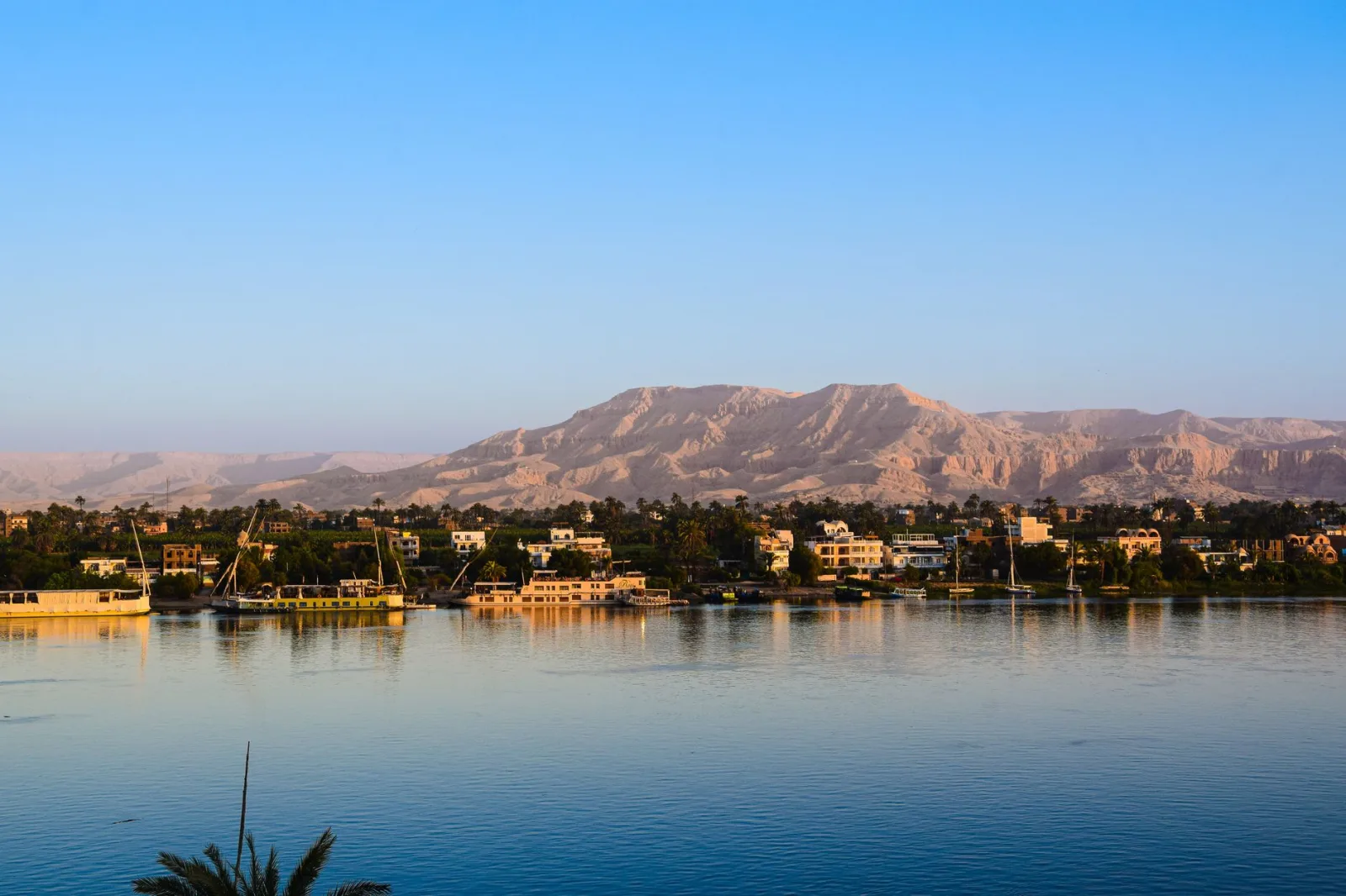 Captivating view of the Nile River with lush greenery and distant desert mountains in Egypt.