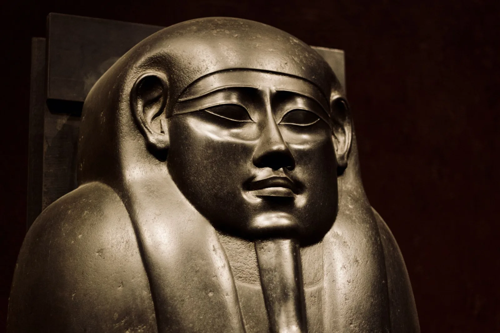 Close-up view of an ancient Egyptian pharaoh statue highlighting intricate details.