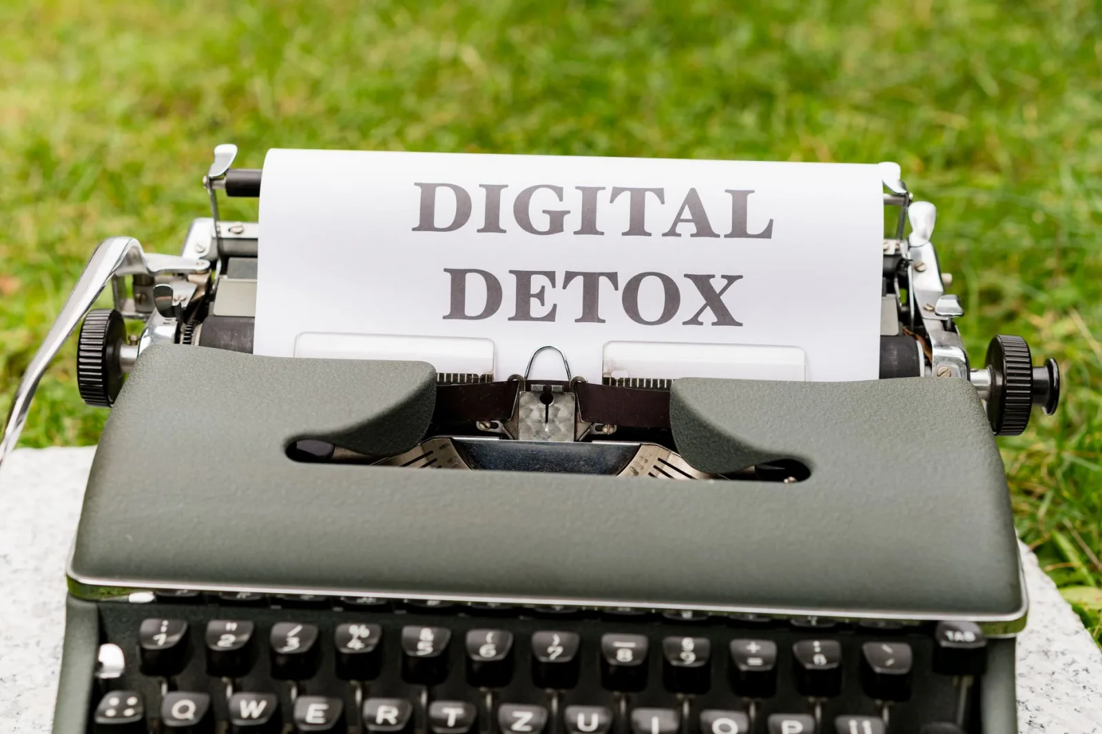 A classic typewriter displaying the words 'Digital Detox' outdoors, symbolizing a break from technology.
