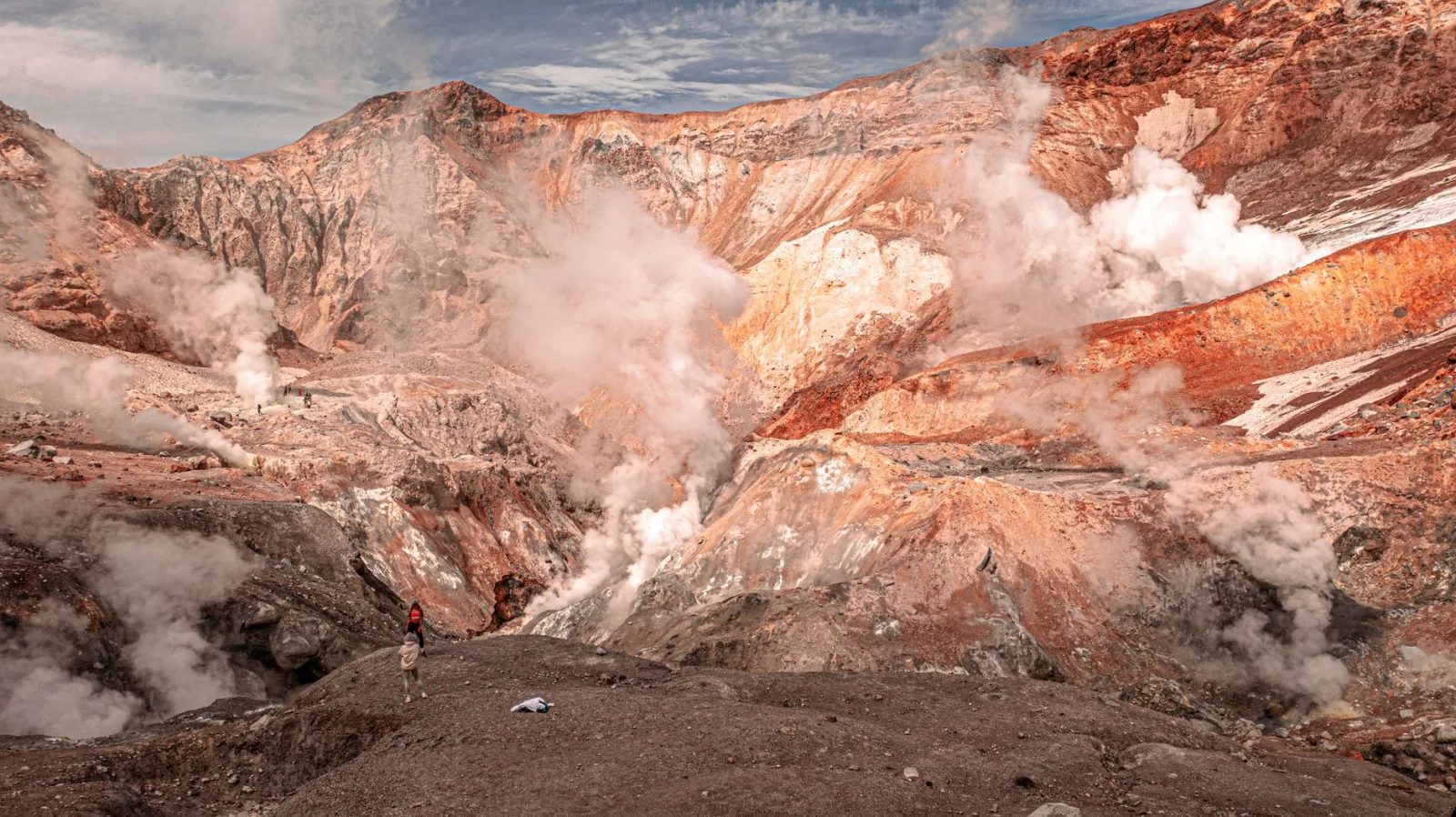 Adventurous hikers exploring the steamy volcanic landscape of Kamchatka, Russia.