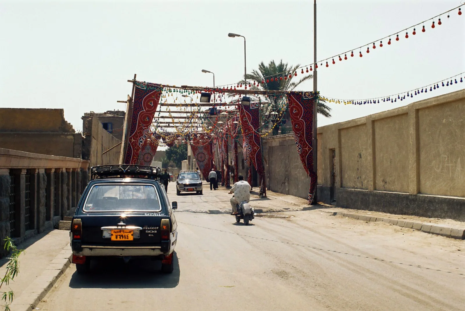 Colorful street decorations in Egypt with vehicles and pedestrian during daytime